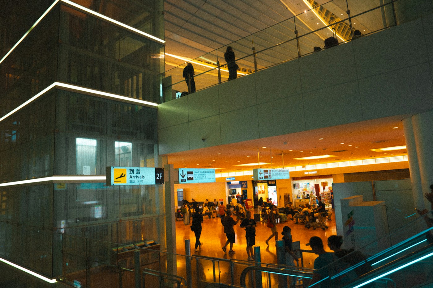 Travelers walking through a warmly lit Japanese airport terminal