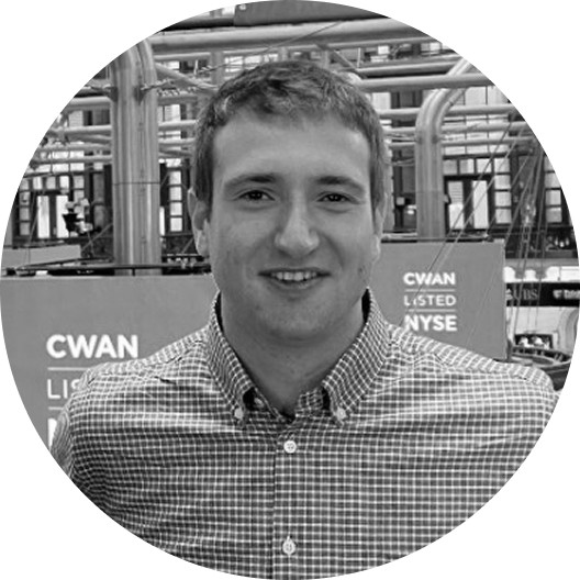 Editorial portrait of a young man with wavy hair in a knit sweater, looking over his shoulder in soft light.