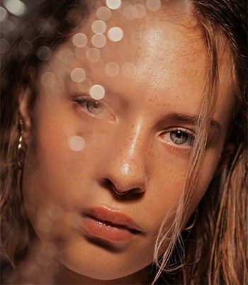 woman peeking over green leaf plant taken at daytime
