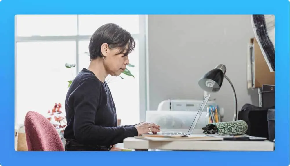 Woman sitting at a desk working on a laptop in a room with natural light