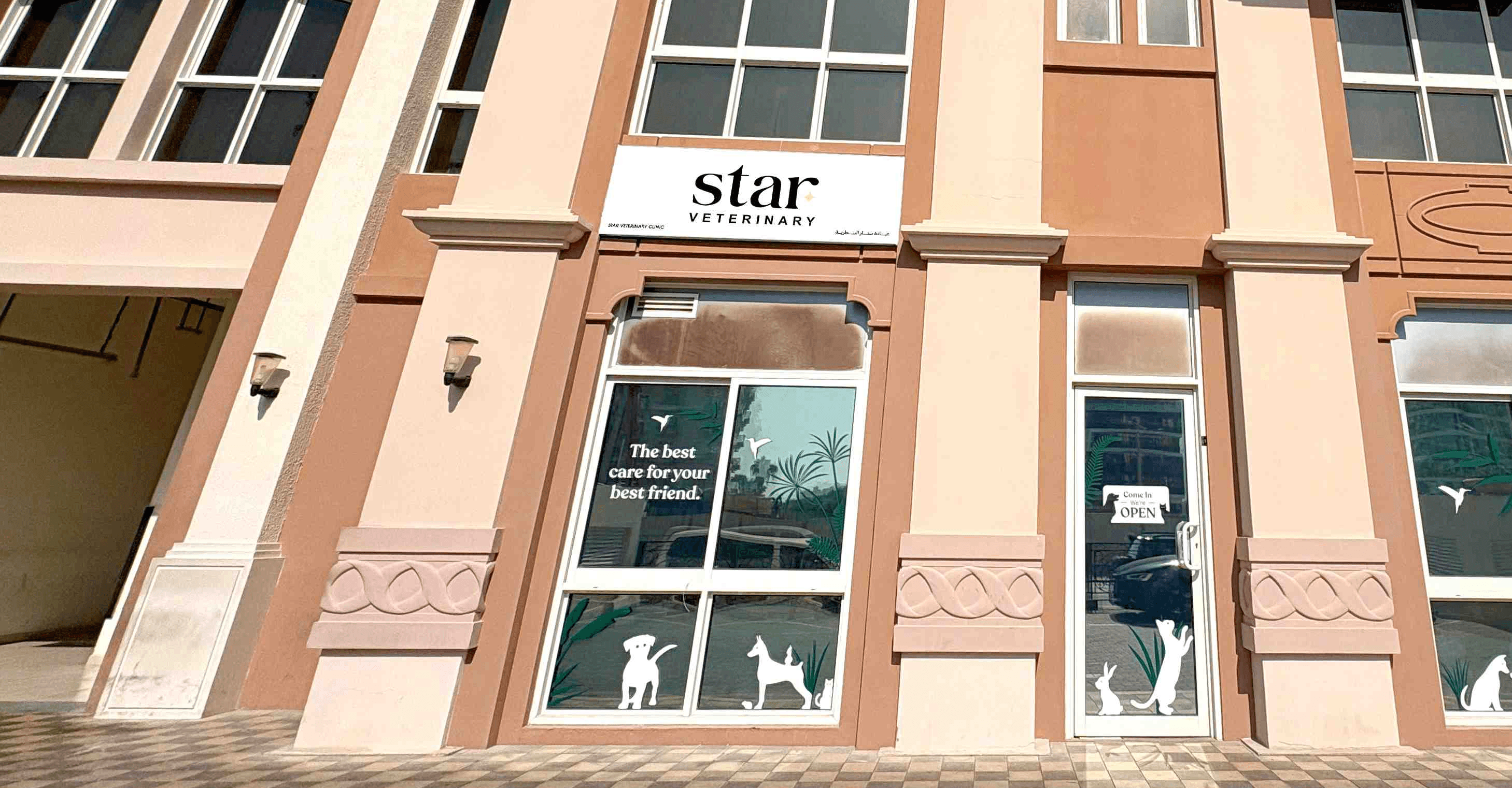 The front of Noble Veterinary Clinic in DIP, Dubai. Our vet clinic features glass doors and windows with reverse silhouettes of pets on the windows surrounding the doors.