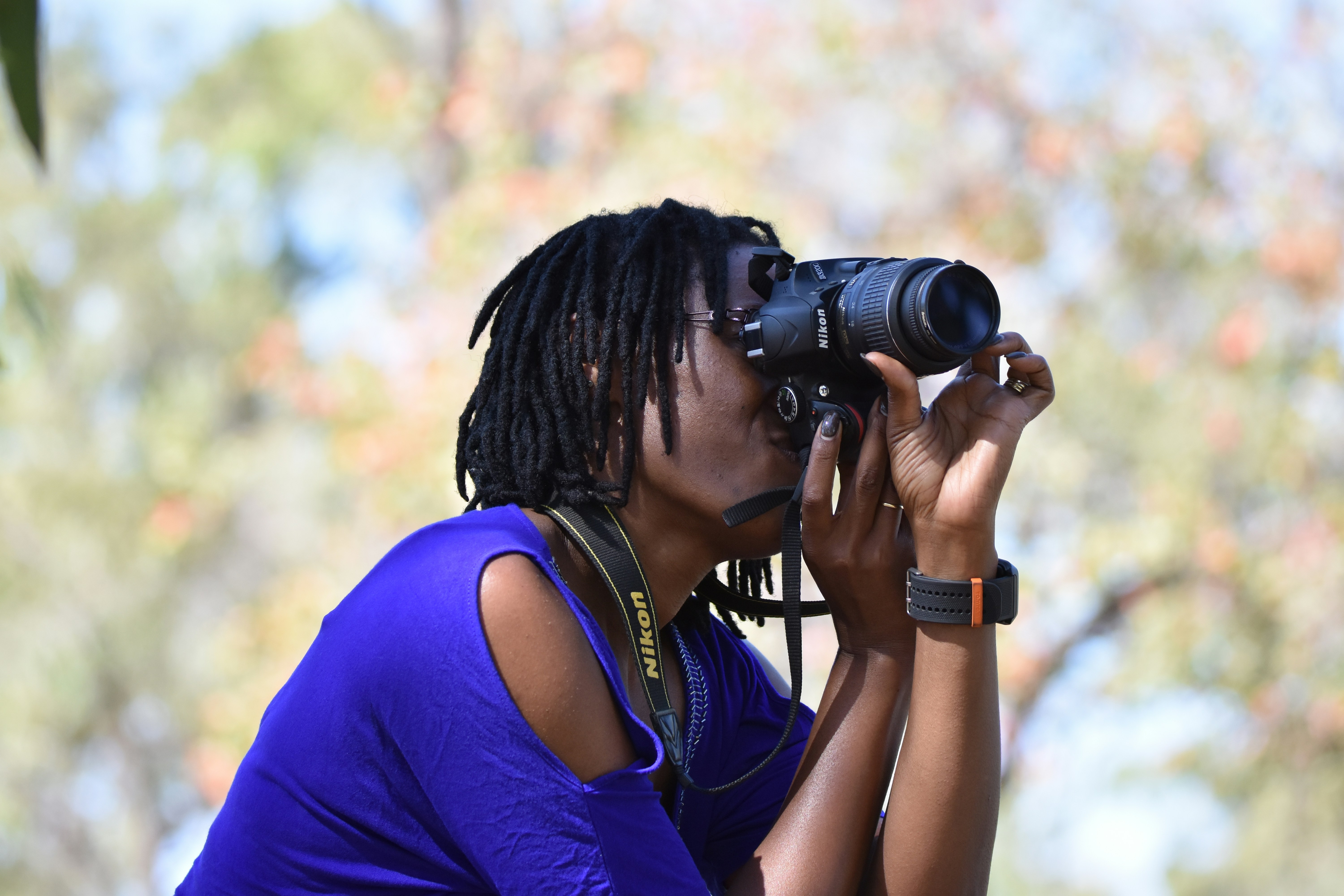 woman in blue cold-shoulder top taking photo using black DSLR camera