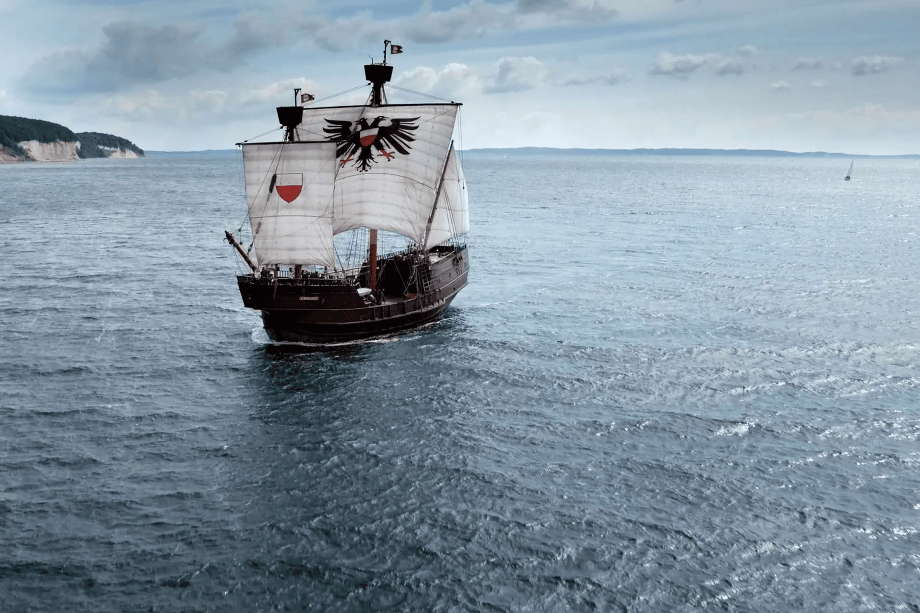 Galleon with eagle flags sails on sea