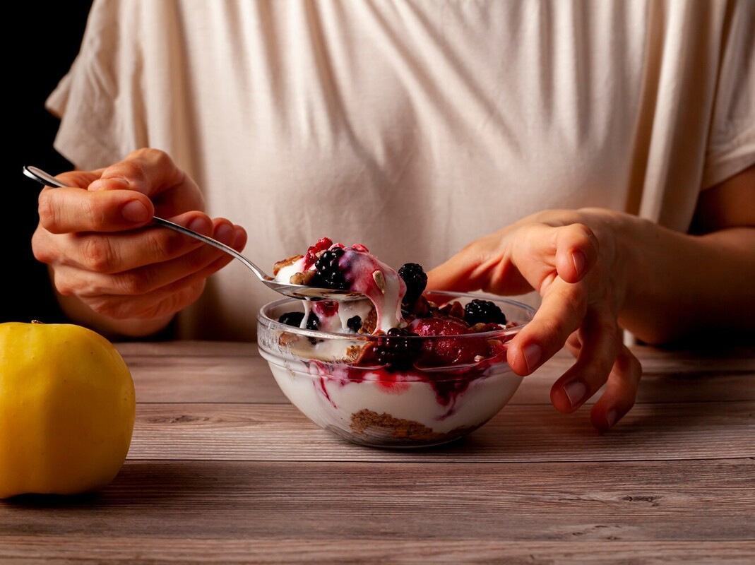 woman eating a healthy snack of yogurt and berries with granola after using a walking pad for weight loss