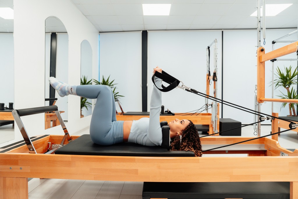 mujer haciendo pilates reformer encima de una maquina Bon Pilates