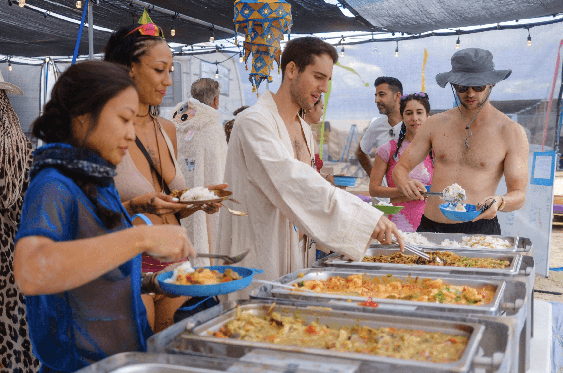 People serving and eating a communal meal together at camp