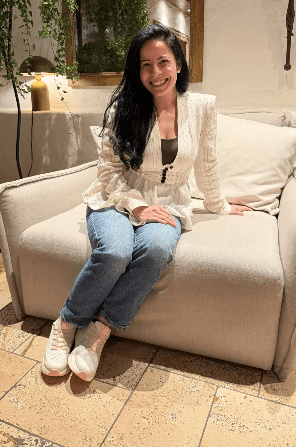 Porträt einer lächelnden Frau auf einem cremefarbenen Sofa