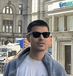 Man in sunglasses and a light jacket in an urban area.