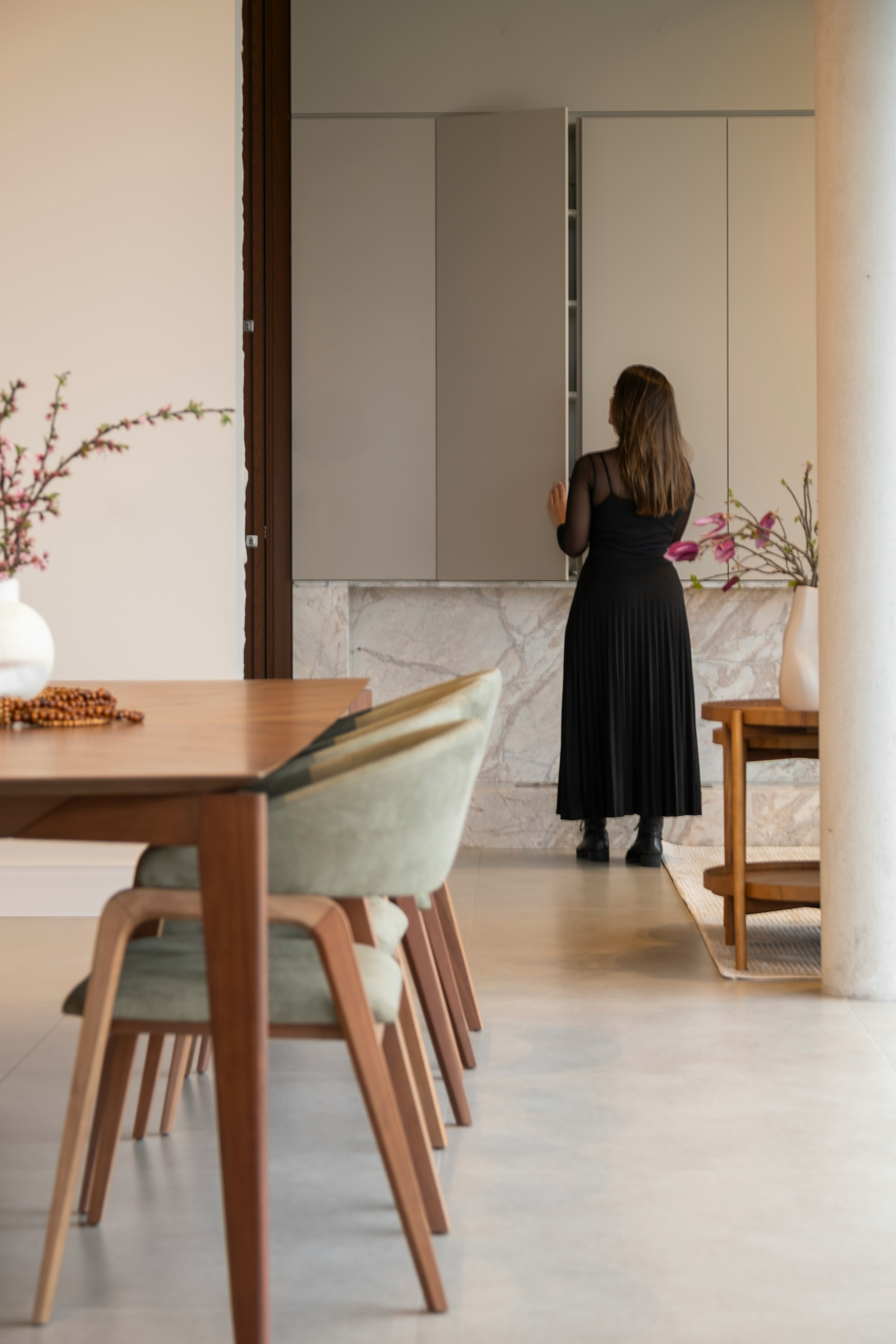 Woman in black dress opening modern kitchen cabinet