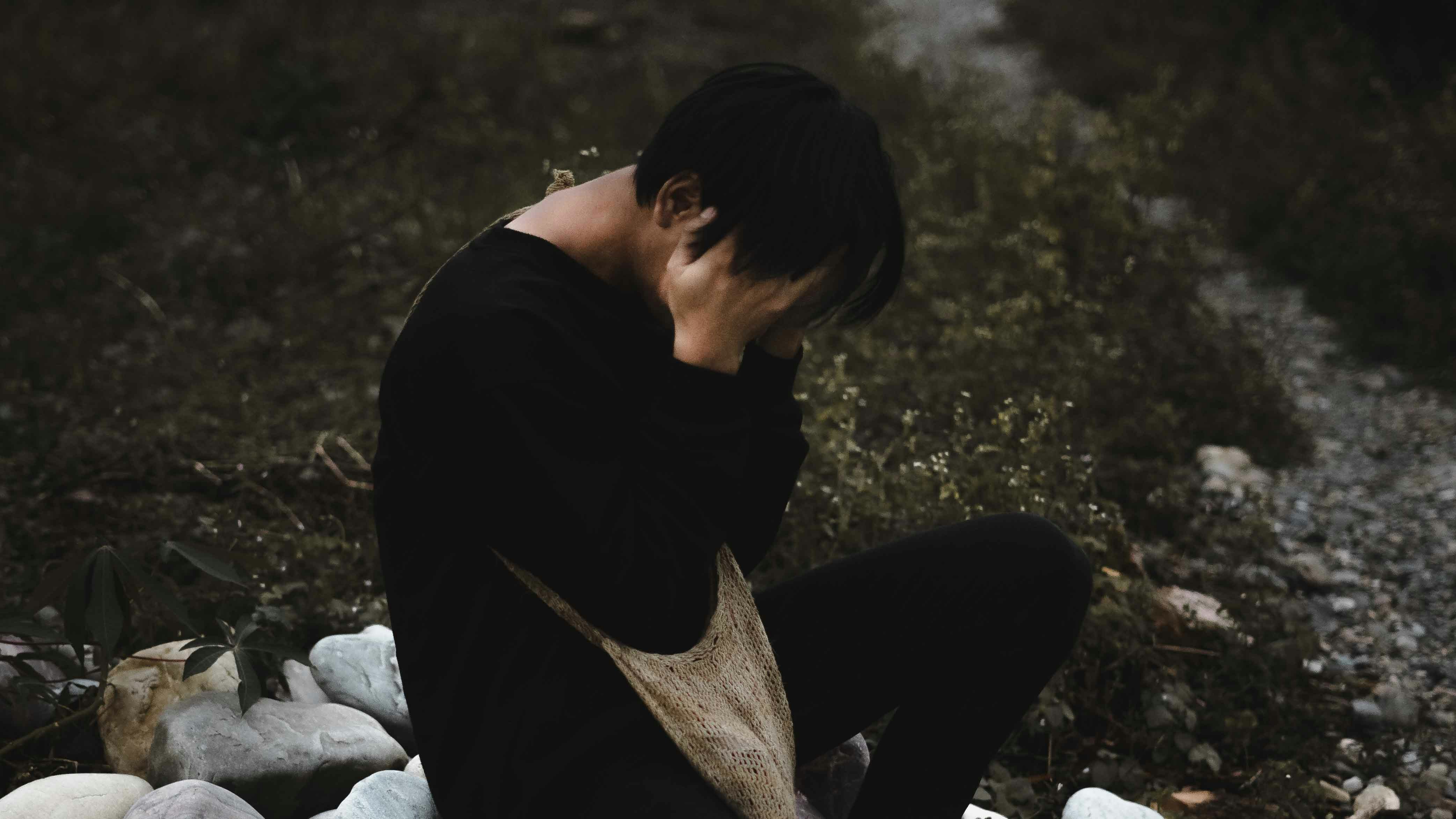 man in black shirt and gray pants sitting on ground