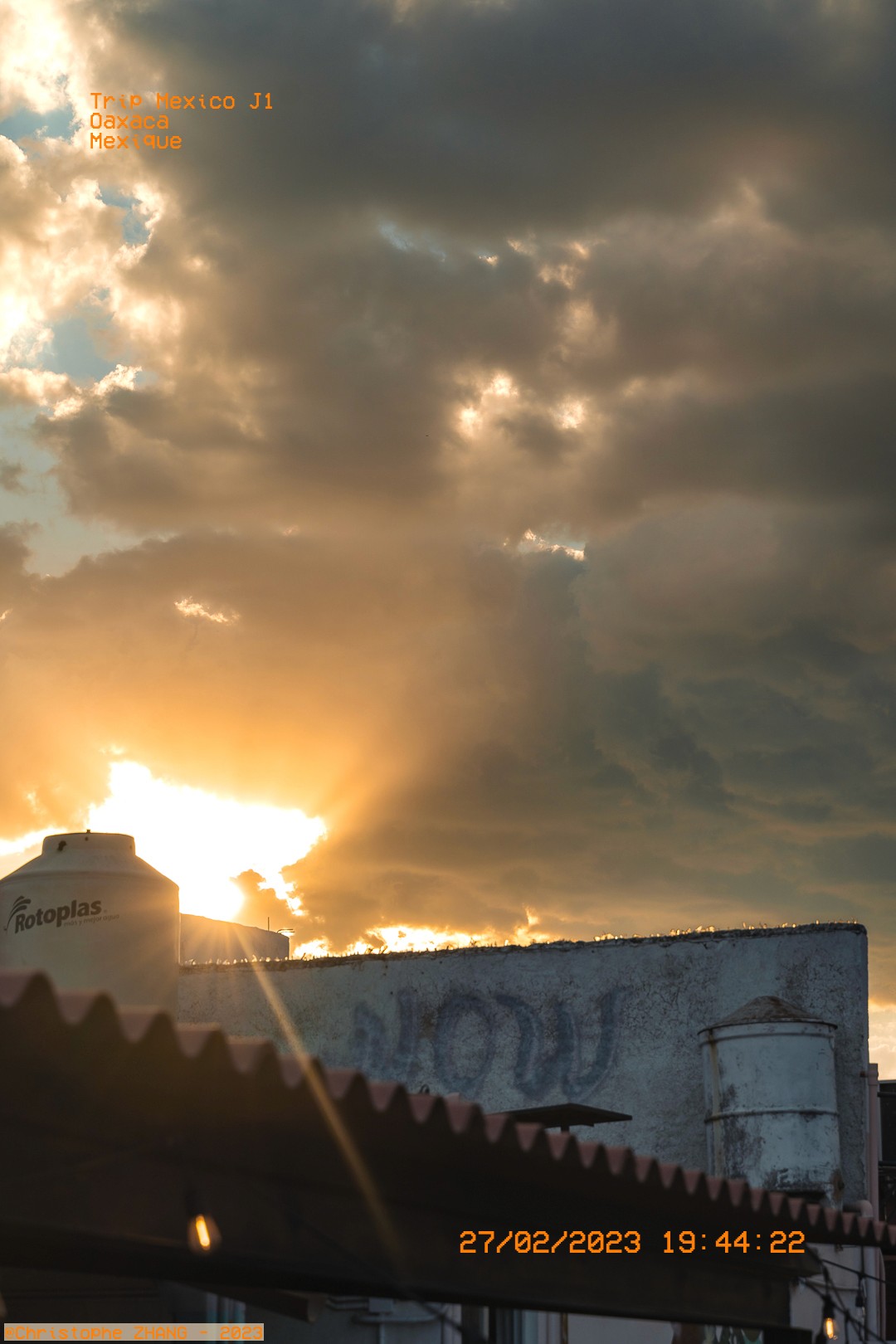 Rayons dorés perçant les nuages derrière un réservoir d’eau.