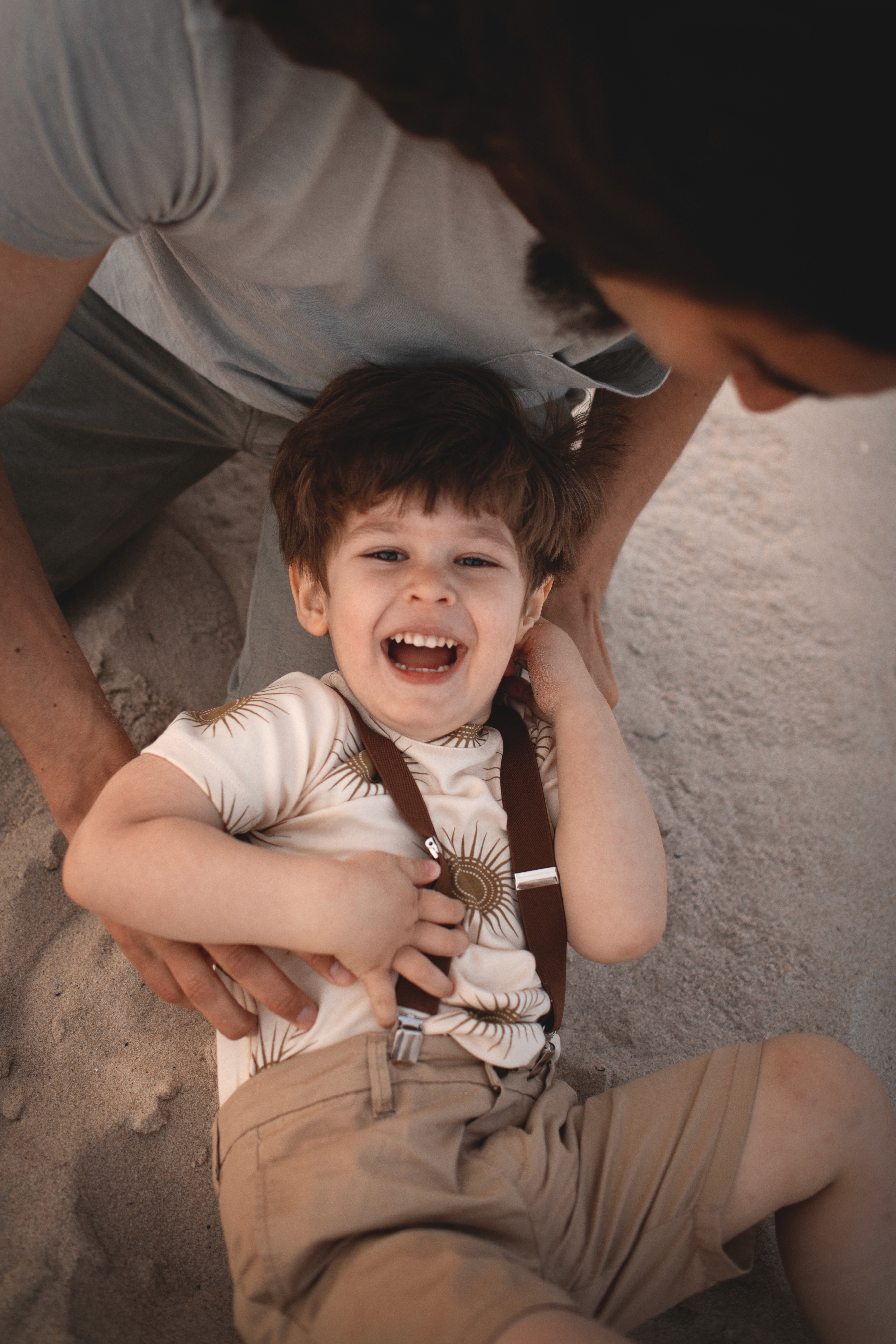 Laughing toddler in his dad’s arms during a warm and natural family photo session