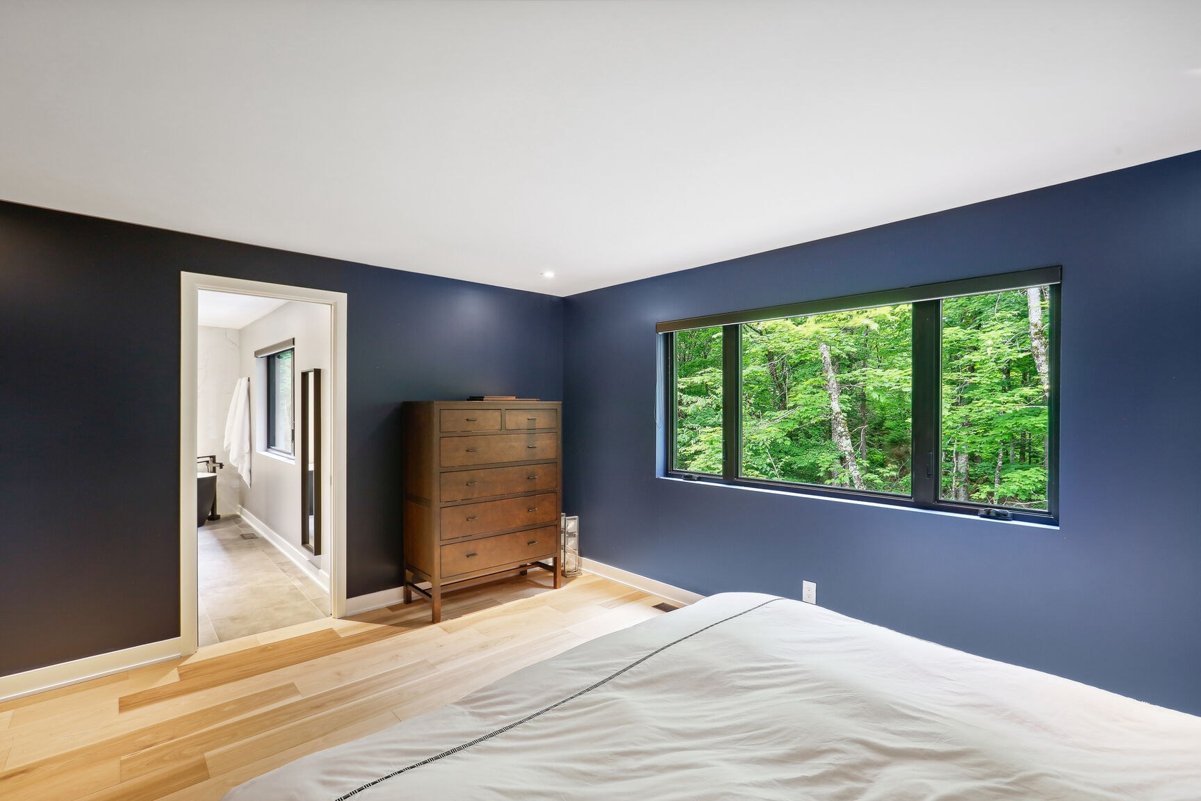Chambre principale avec vue vers la salle de bain attenante.