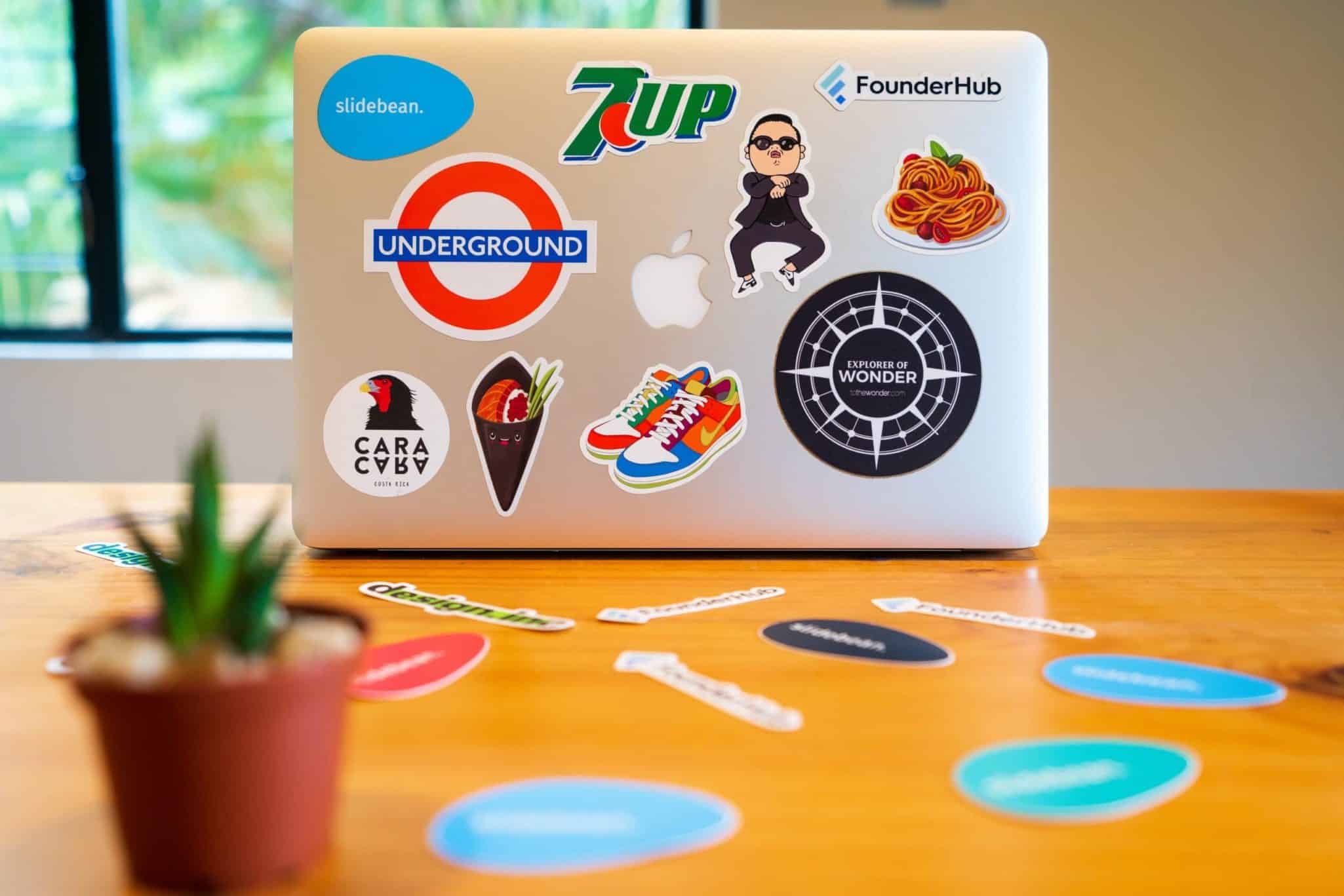 Laptop covered with colorful stickers on a wooden table.