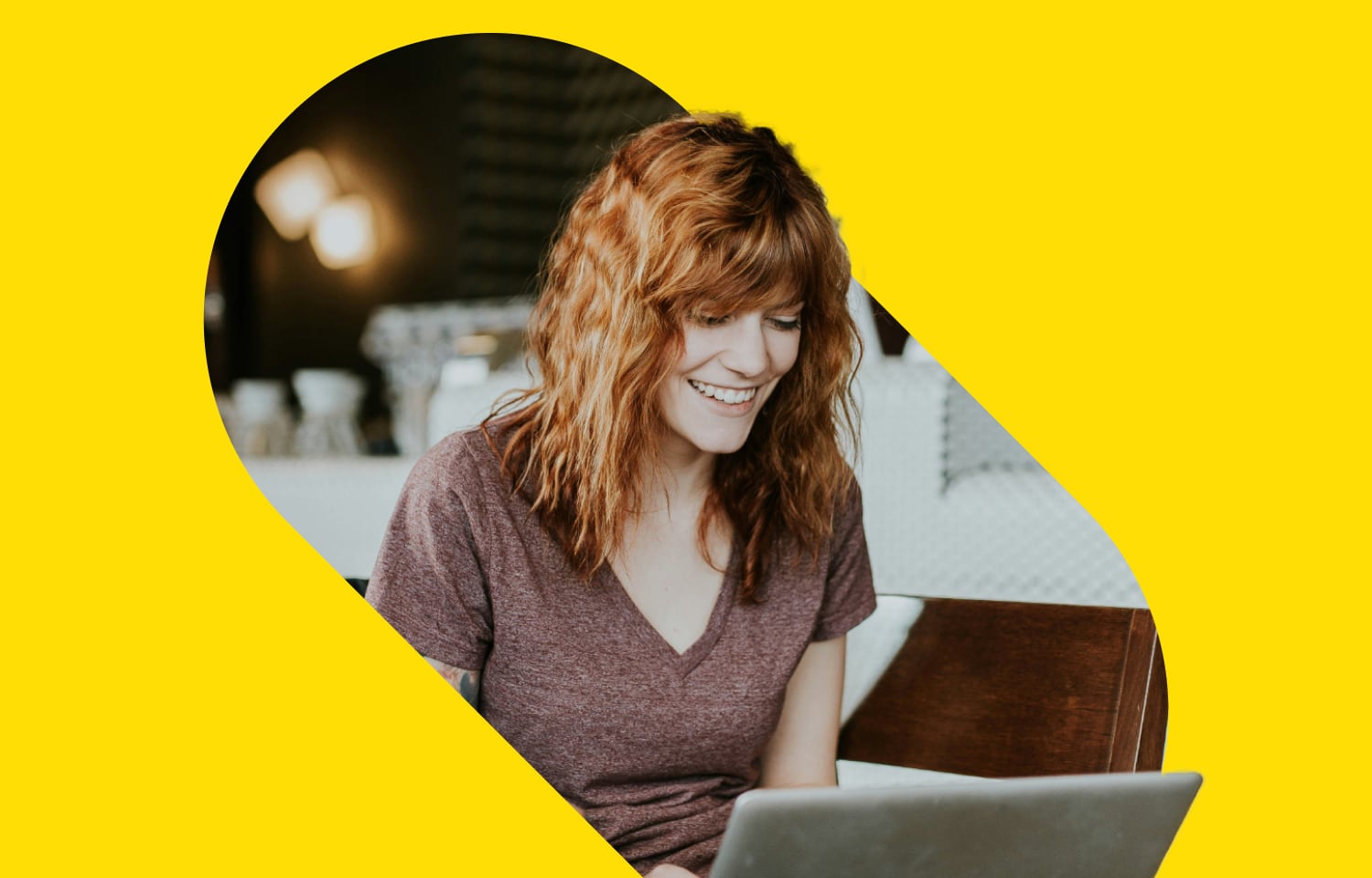 A smiling woman watching a webinar on a laptop