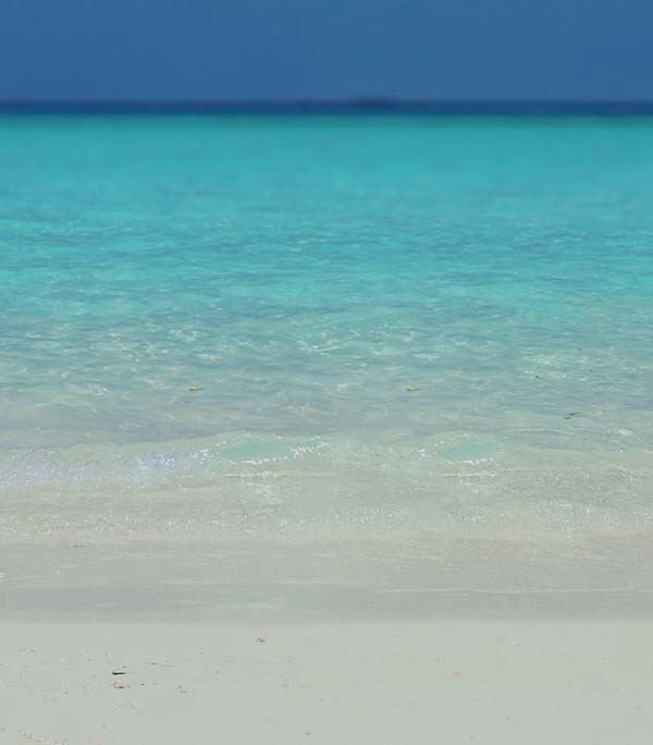 A photo of white sand beach, azure water and blue, clear horizon