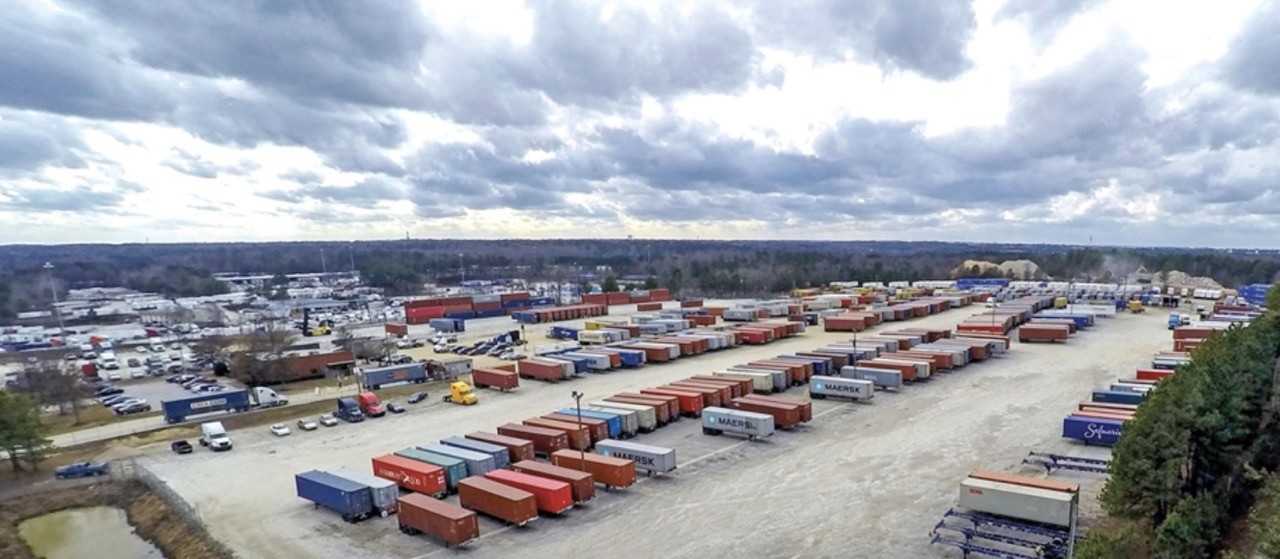 Aerial view of a shipping container storage yard under an overcast sky