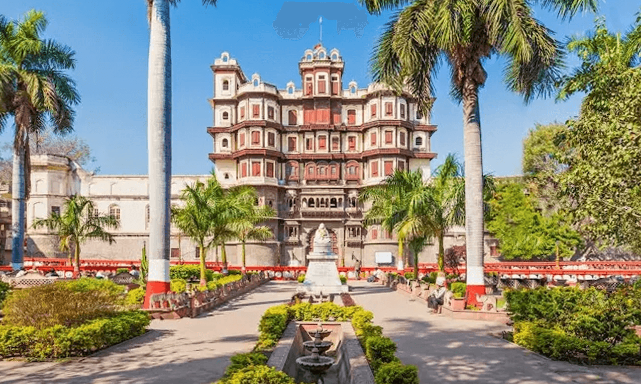 Image of the Rajwada Palace in Indore surrounded by palm trees and gardens.