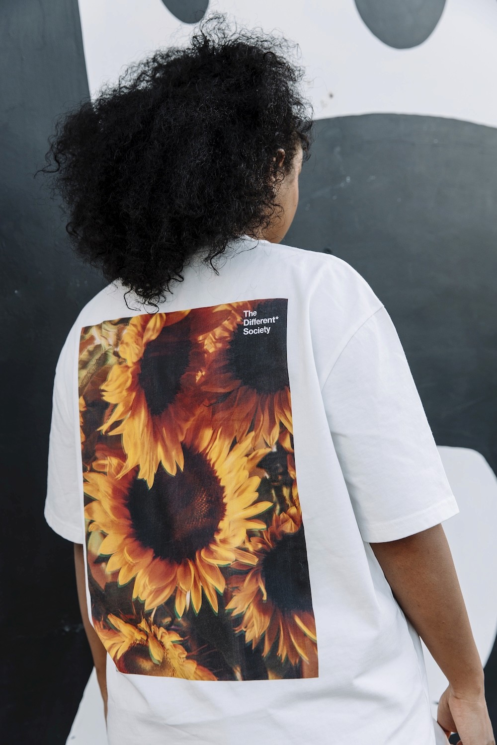 The back of a white t-shirt, with a print featuring several yellow sunflowers