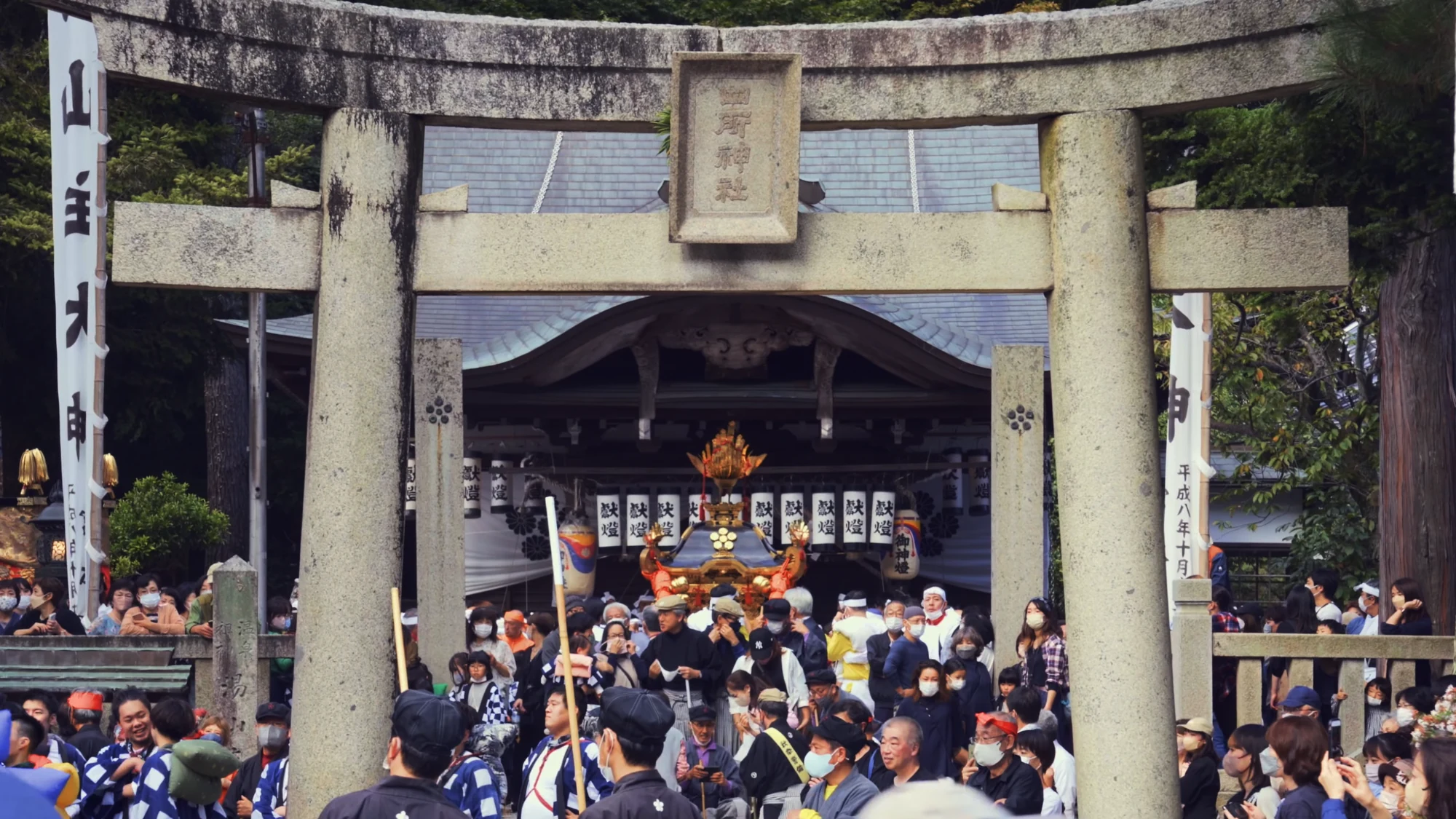 Festival crowds gathered under the stone torii of Shisho Shrine in Kinosaki.