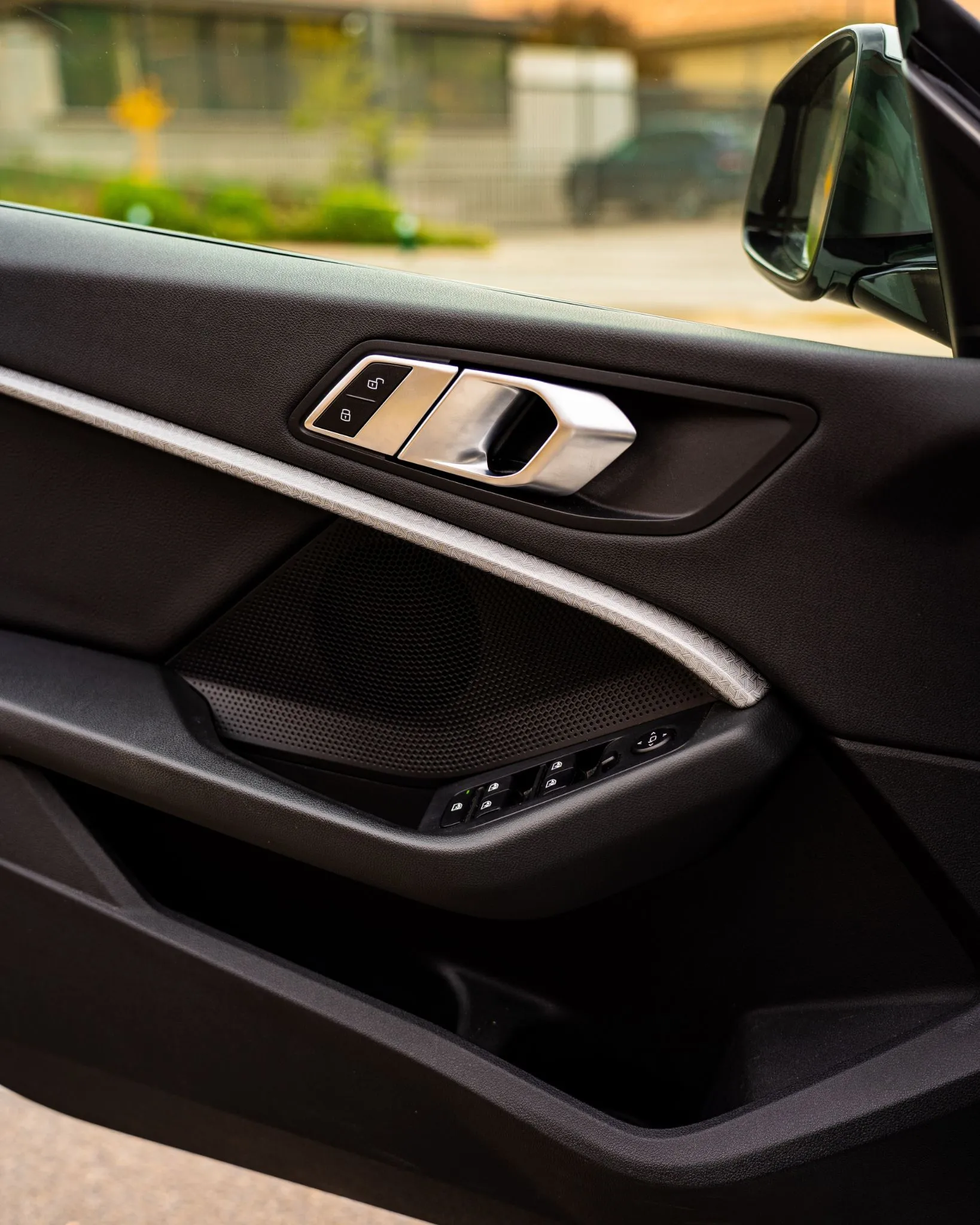 Manilla interior de puerta del BMW 220d con botones de bloqueo, moldura metálica y parlante inferior