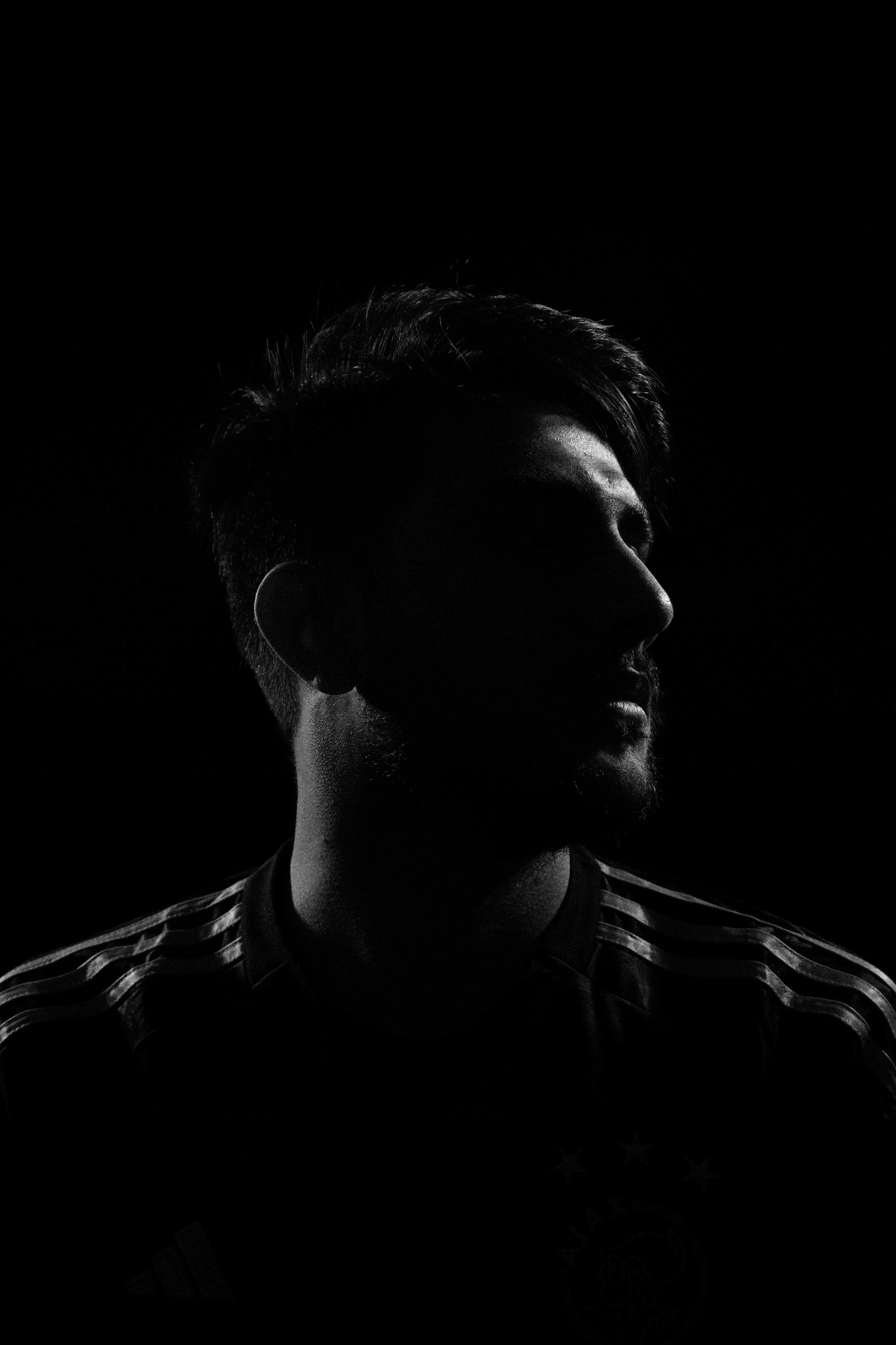 A man standing in the dark with his eyes closed