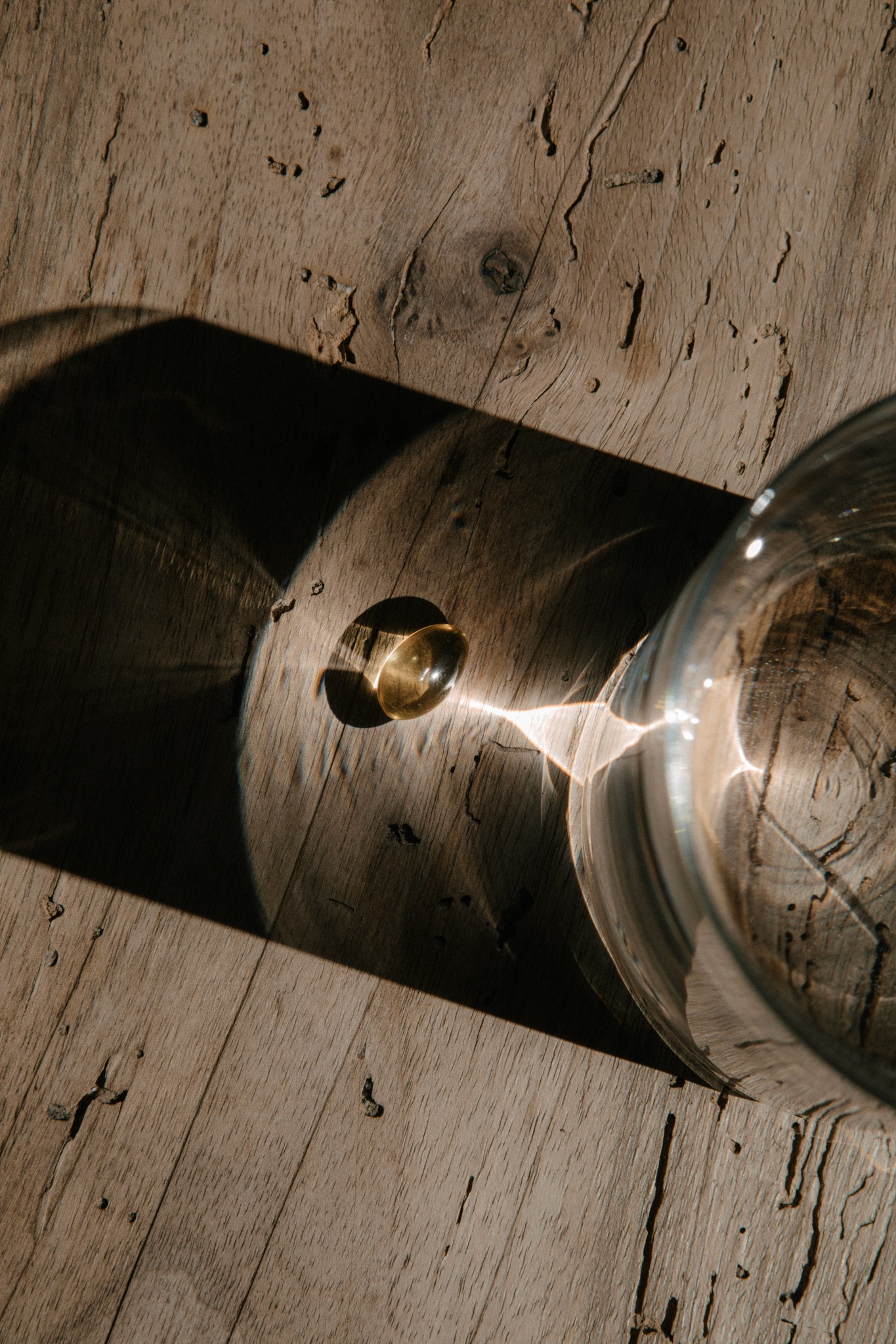 Sonnenlicht fällt durch Glas auf Holztisch mit Omega-3 Softgel-Kapseln