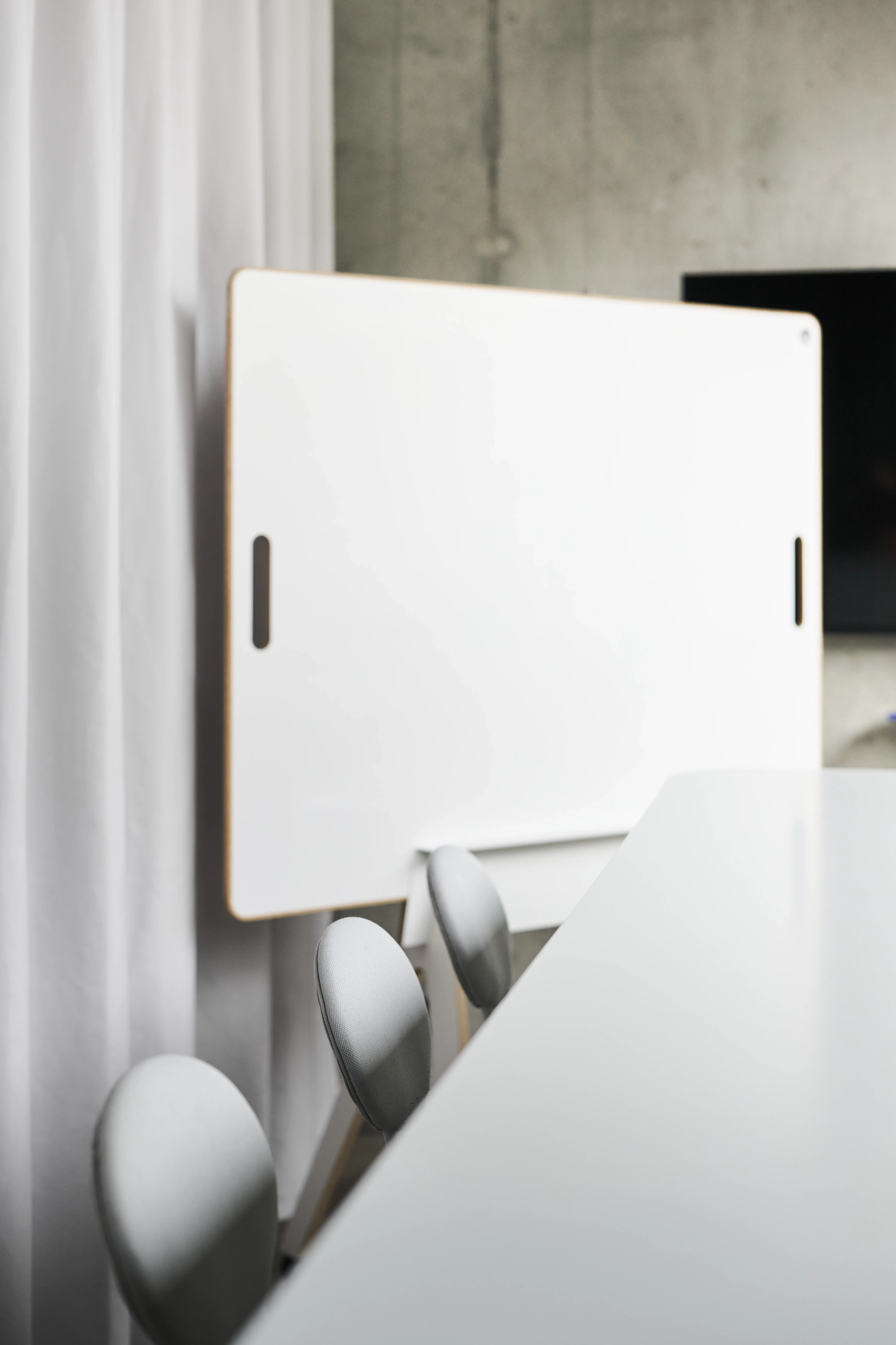 Mobile white whiteboard with wooden edge and handle cutouts beside the white conference table in the UNDPLUS SHOWROOM.