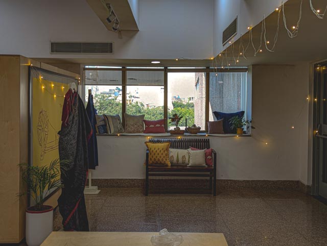 ozy Breakout Space: A sunlit window nook adorned with vibrant Khadi cushions and soft fairy lights creates a relaxed, informal corner for creative discussions.