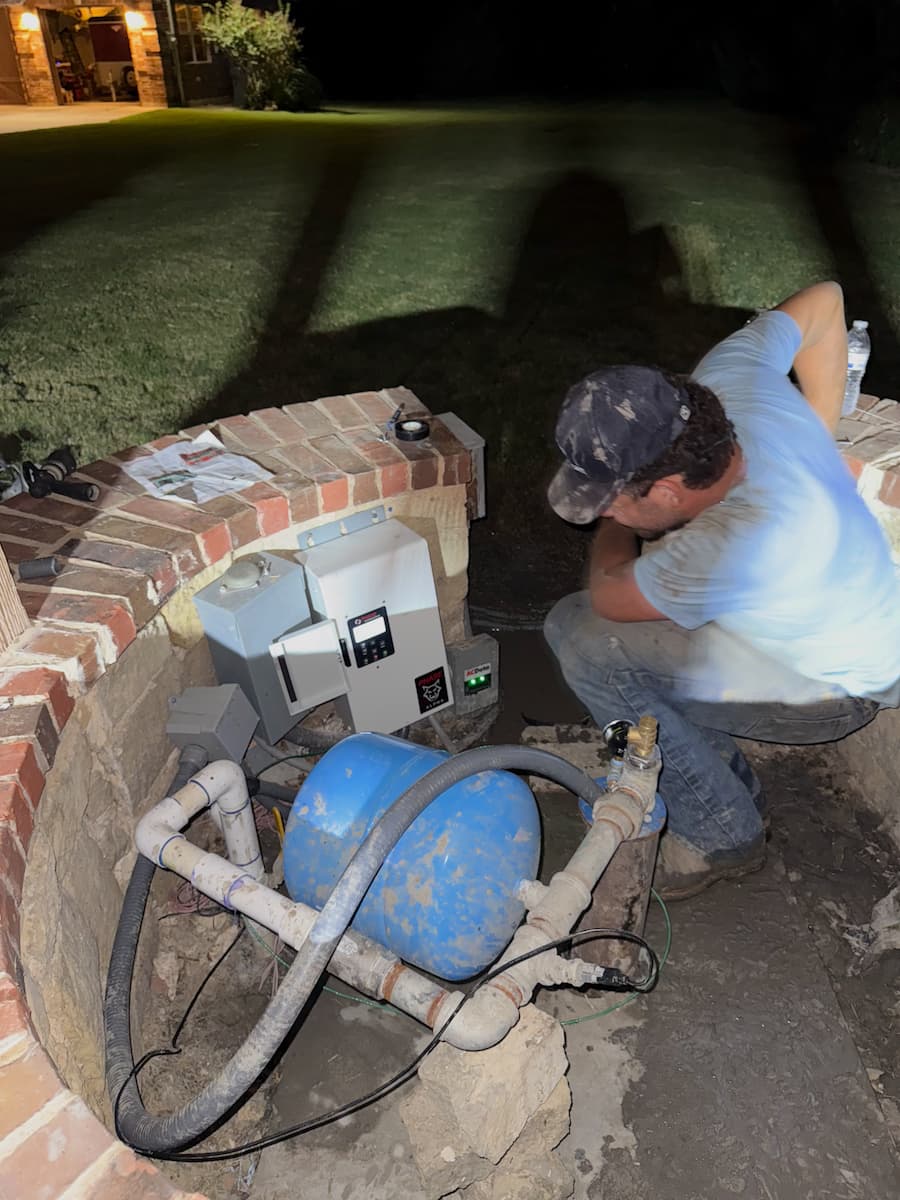 Flowcore technician installing a pump control box and pressure tank at a well house