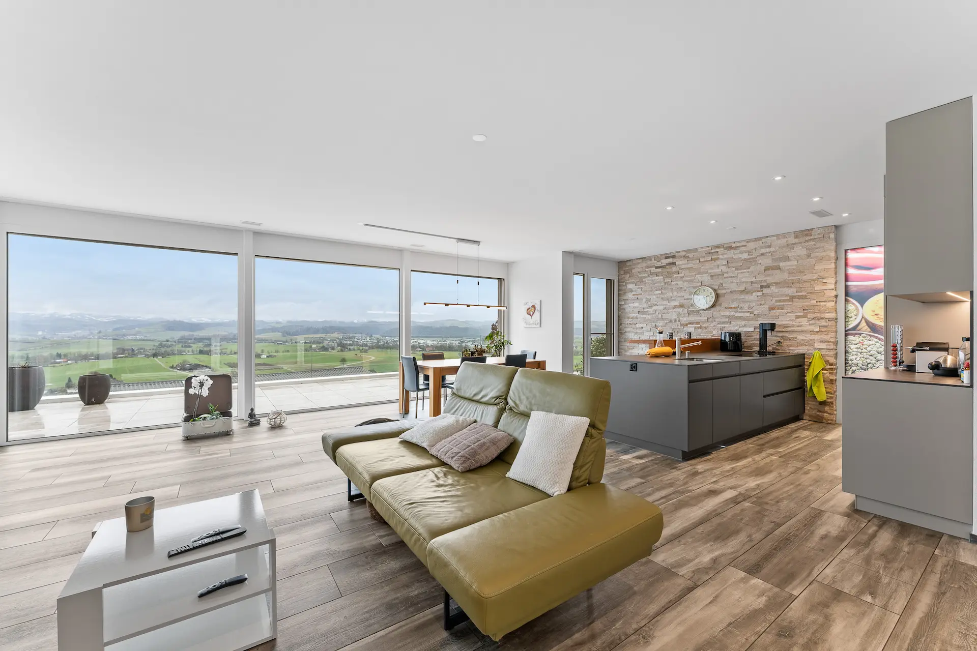 Grünes Ledersofa im Wohnzimmer mit Panoramablick und grosser Fensterfront