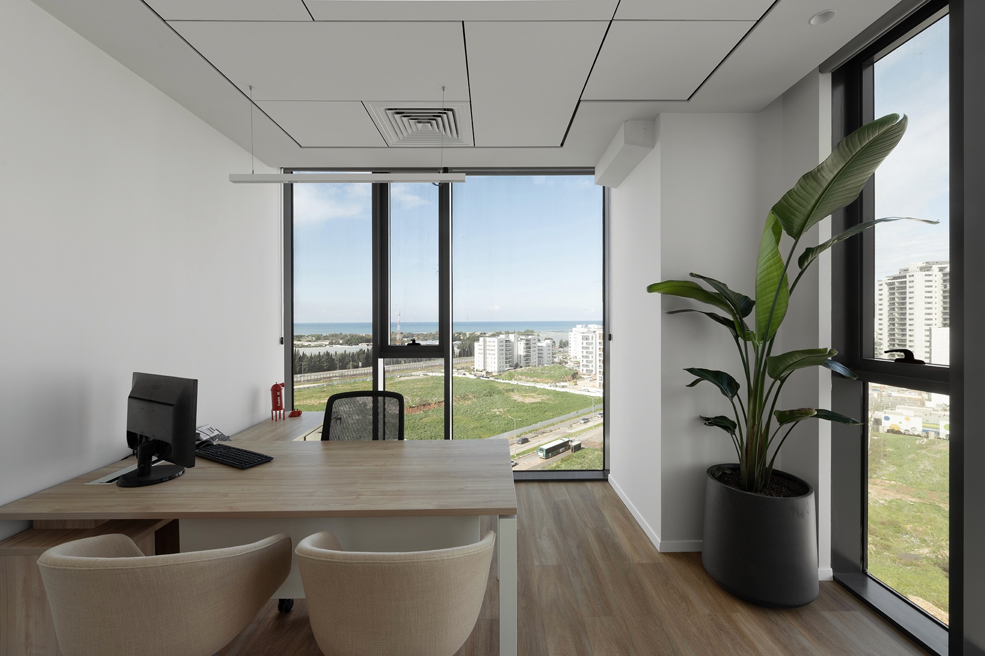 משרד מנהל במיקום אסטרטגי: ניצול מקסימלי של אור טבעי (Daylight Harvesting) ונוף לים, עם דגש על עיצוב נקי ושילוב צמחייה