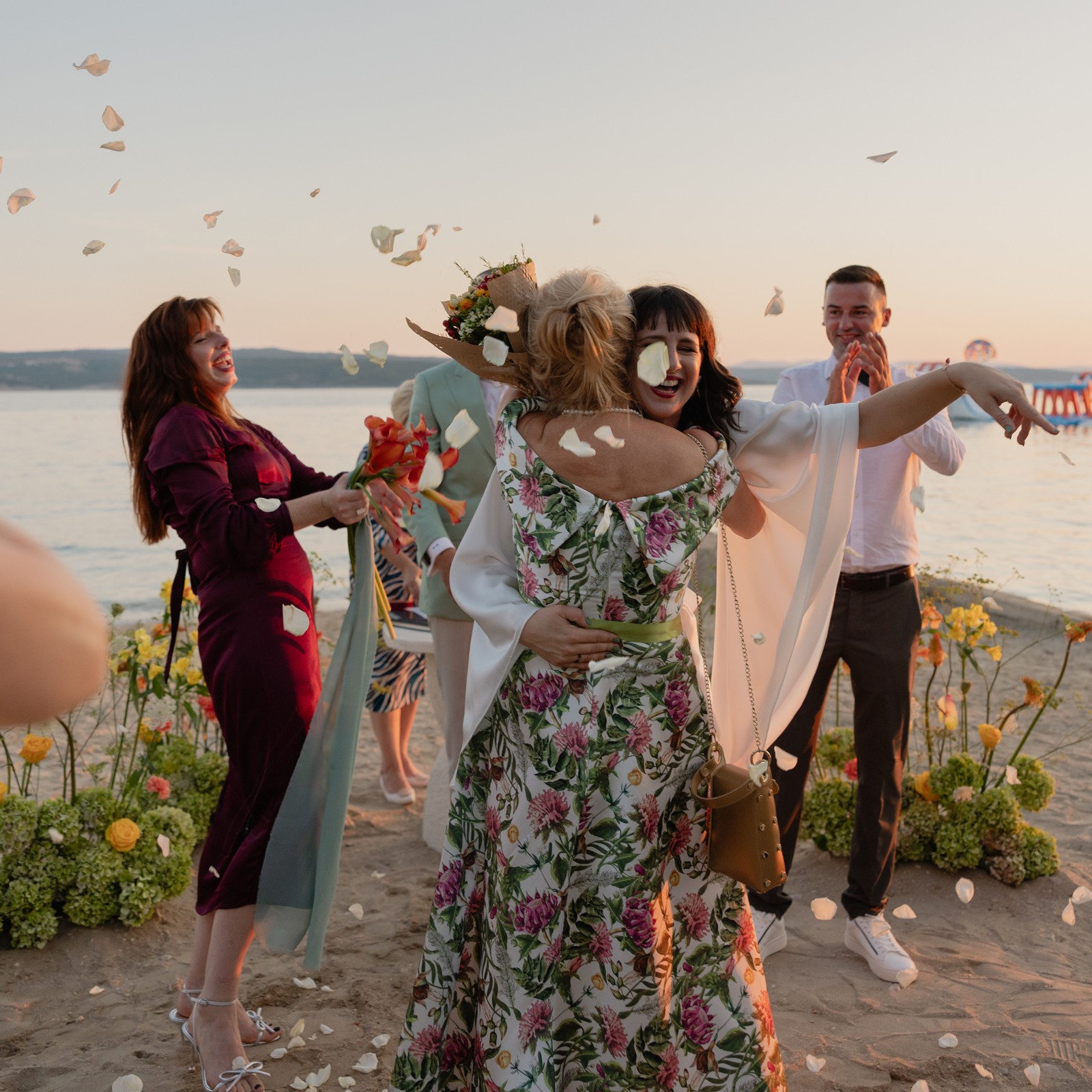 Wedding on the beach with people celebrating with the bride with flower petals falling around