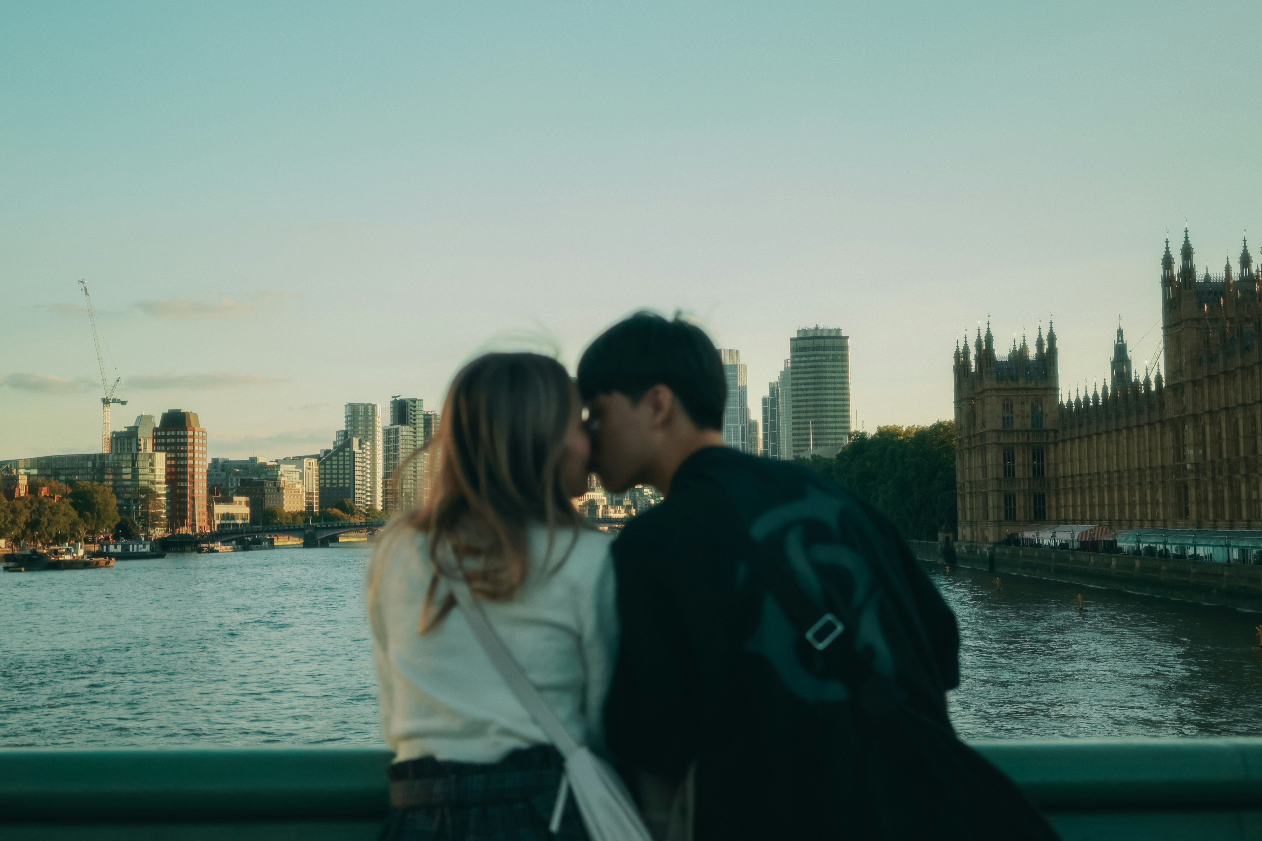 Couple kissing on a bridge with city skyline