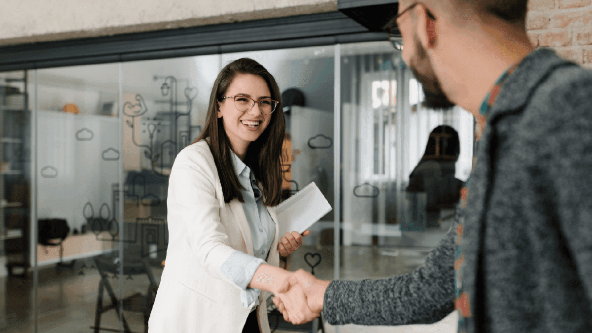 Professional woman shaking hands at a job interview in a modern office with glass walls