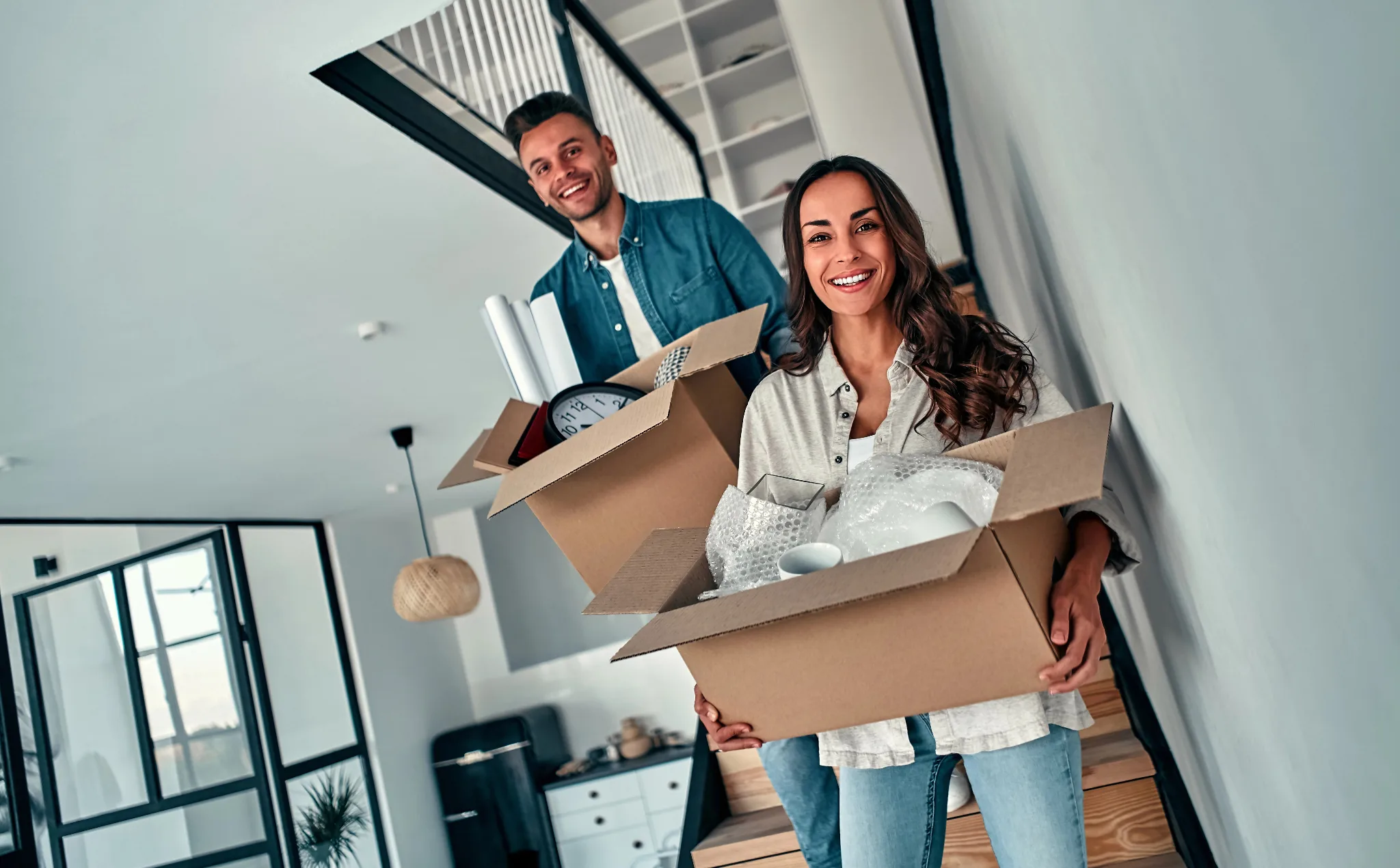 A man and woman holding moving boxes into their new home.