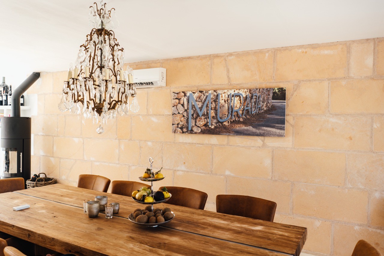 Esszimmer mit Holztisch, Kronleuchter und Steinwand. Gemütliches Ambiente.