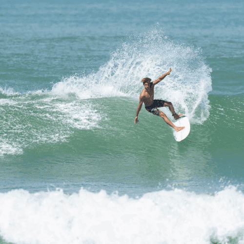 Surfer riding waves on a white surfboard – surfboard rental in dominical