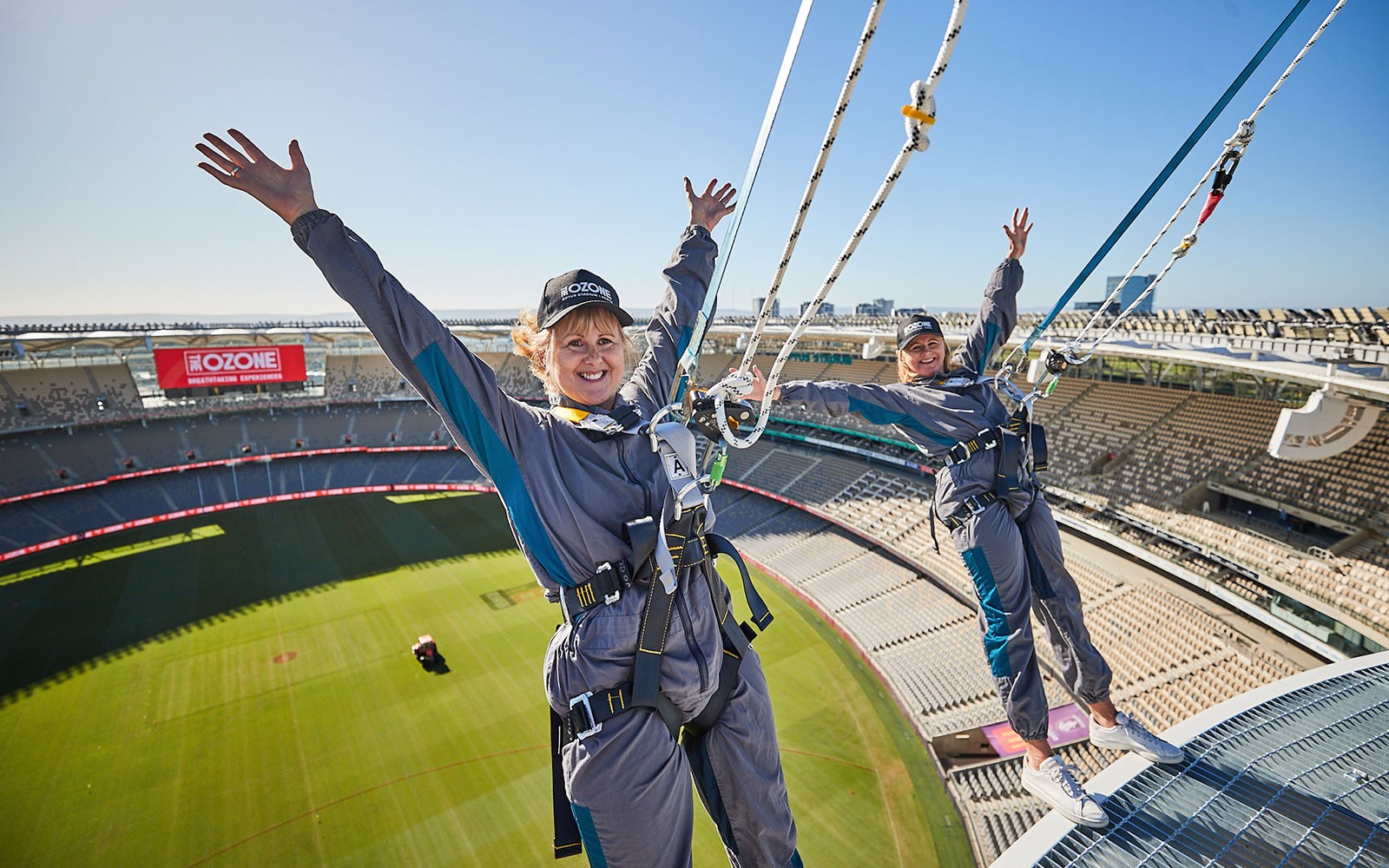 Participants harnessed on Optus Stadium roof during Vertigo experience in Perth, Australia.