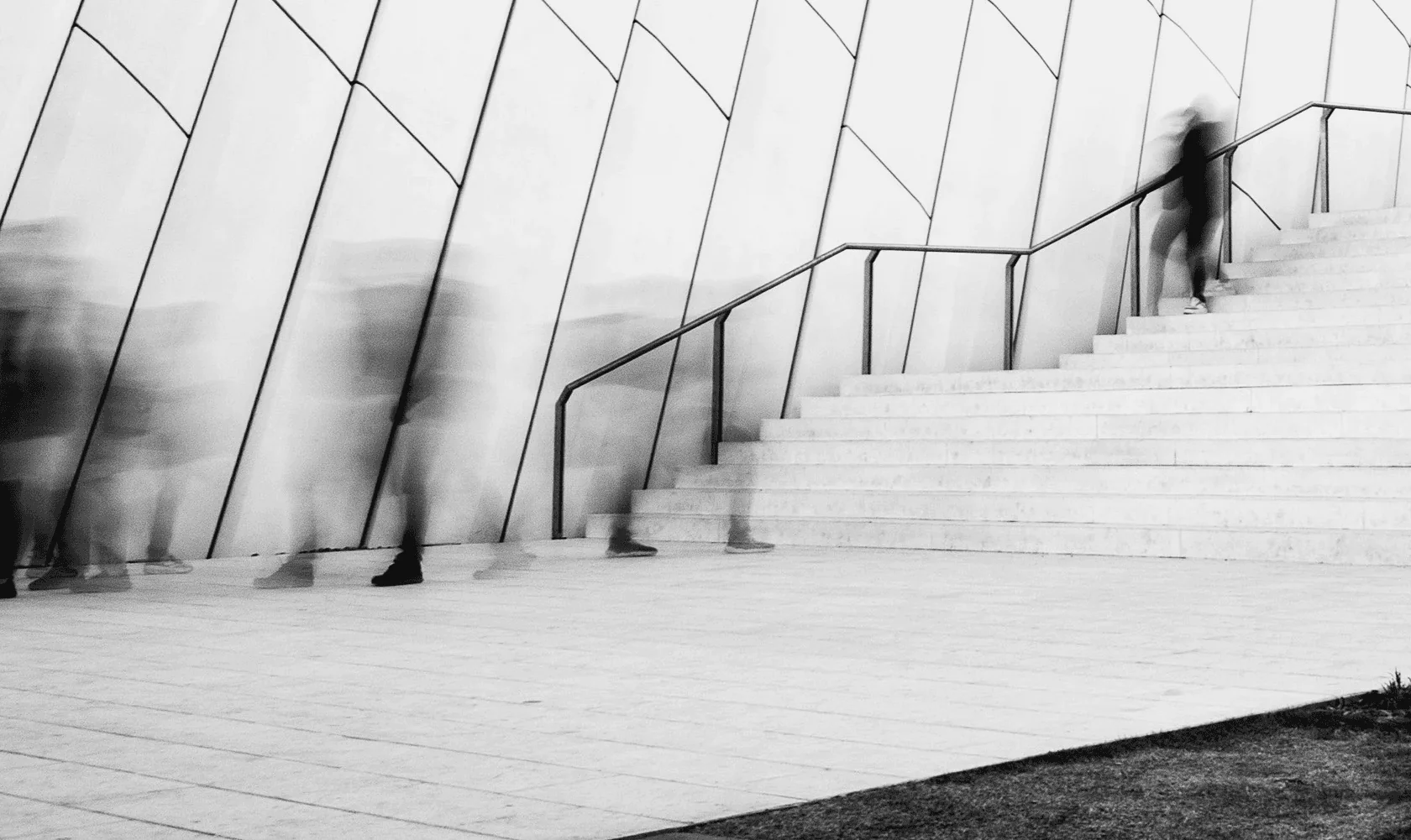 Blurred figures walking past a modern building and staircase