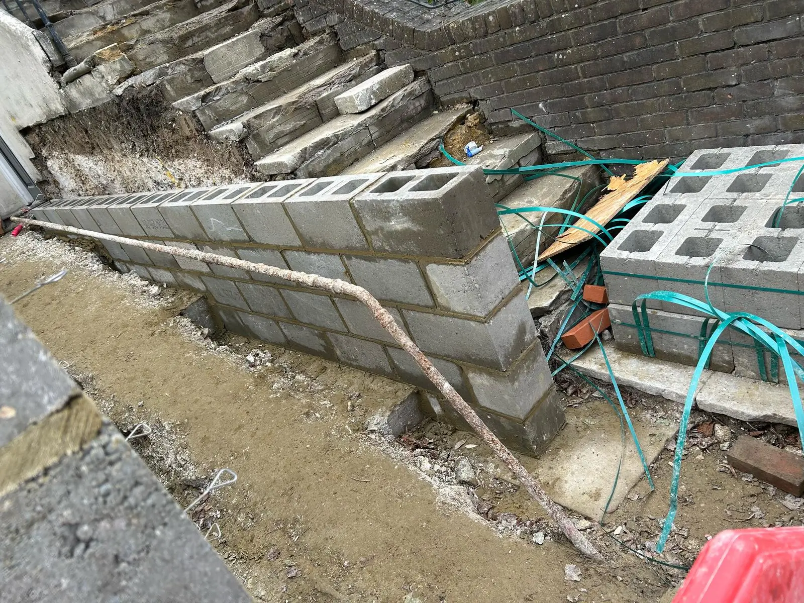Aerial view of a construction site with exposed foundations and nearby buildings amidst muddy water.