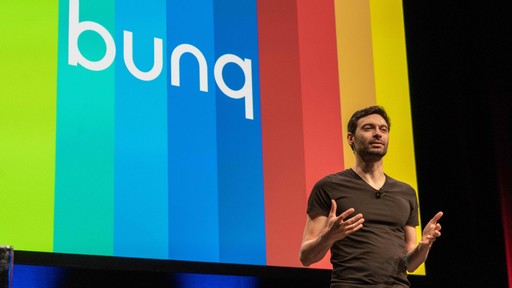 Speaker giving a presentation on stage with a colorful bunq logo in the background.