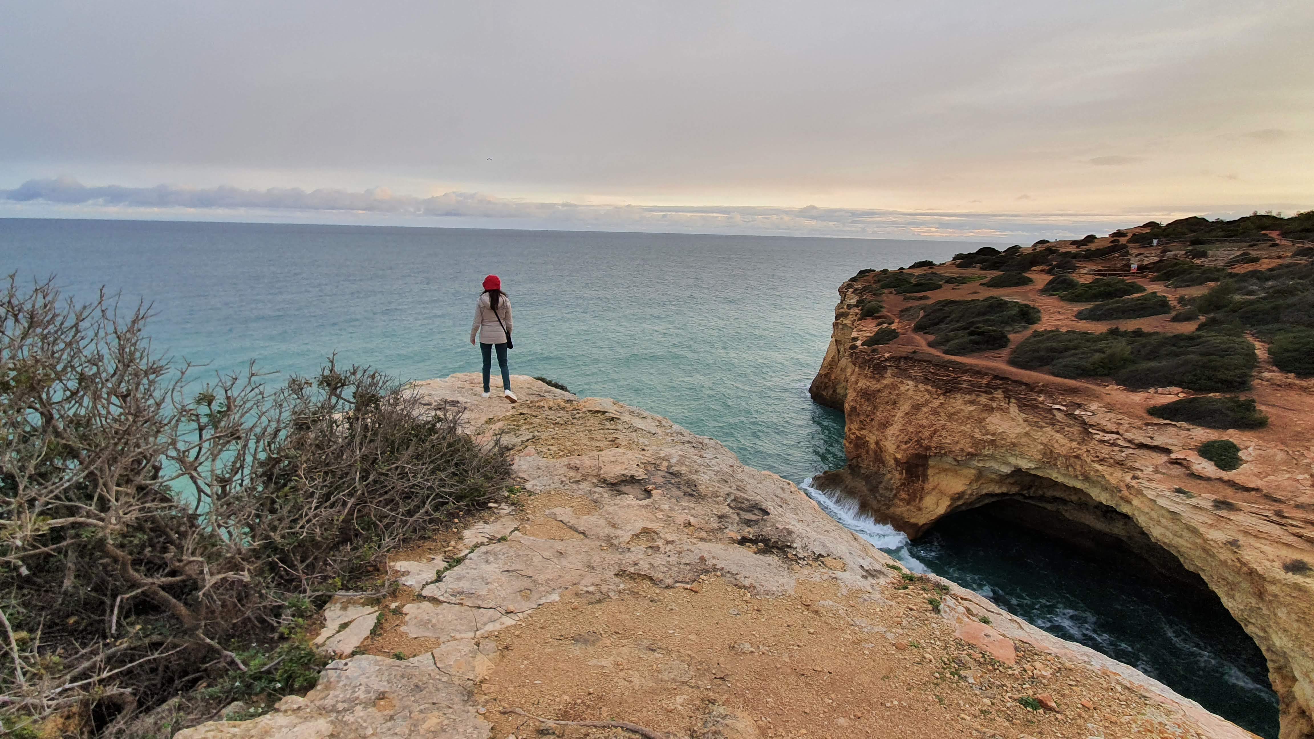 Samira standing at edge of cliff looking at clouds