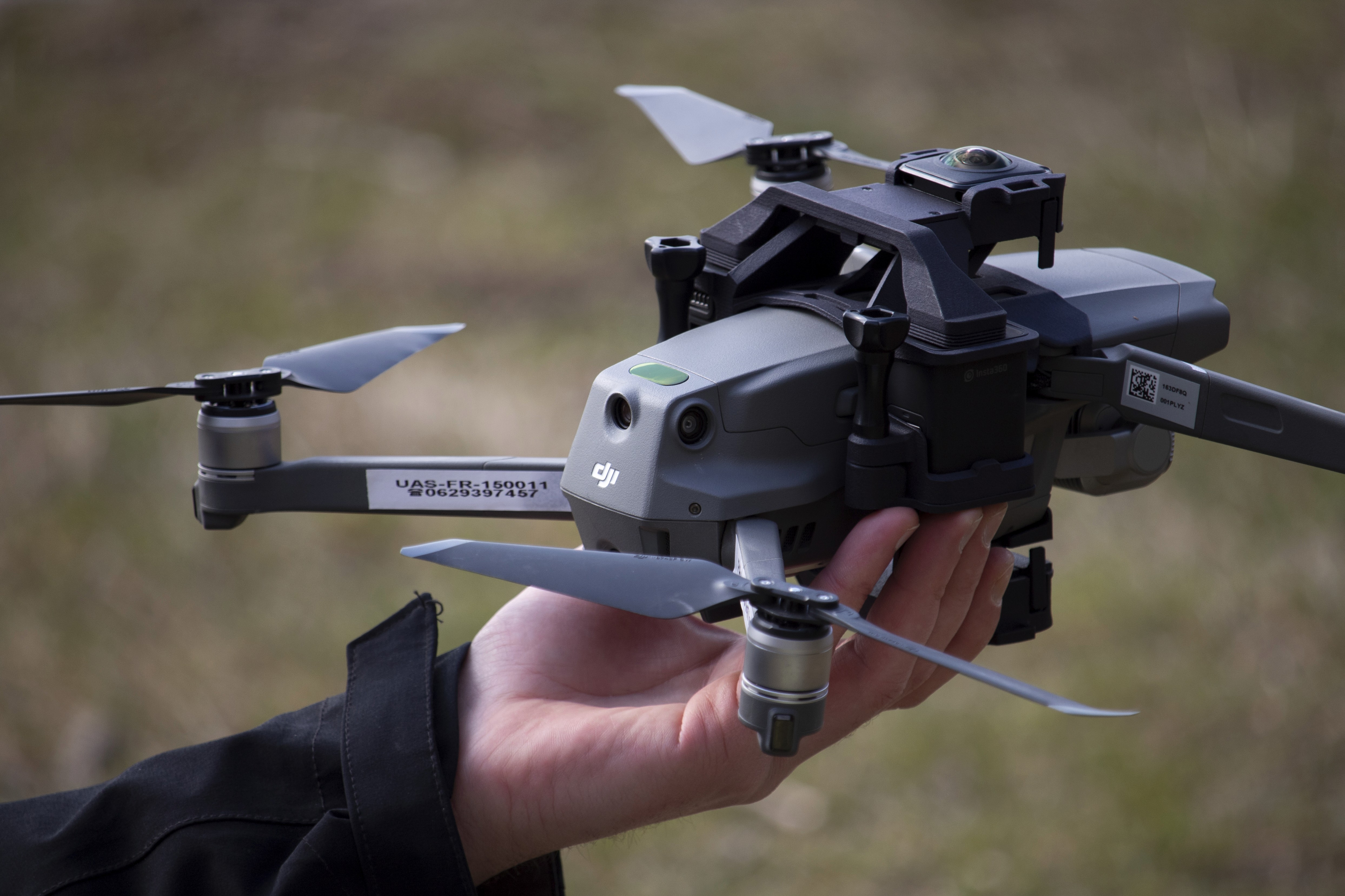 A black Leica camera with a textured body is dramatically lit in red, reflecting on a glossy surface. The red background adds a bold, intense mood.