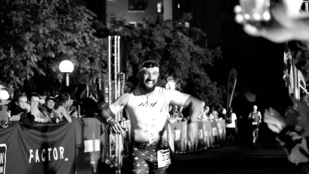 Looping monochrome footage of a runner celebrating at a night marathon finish line