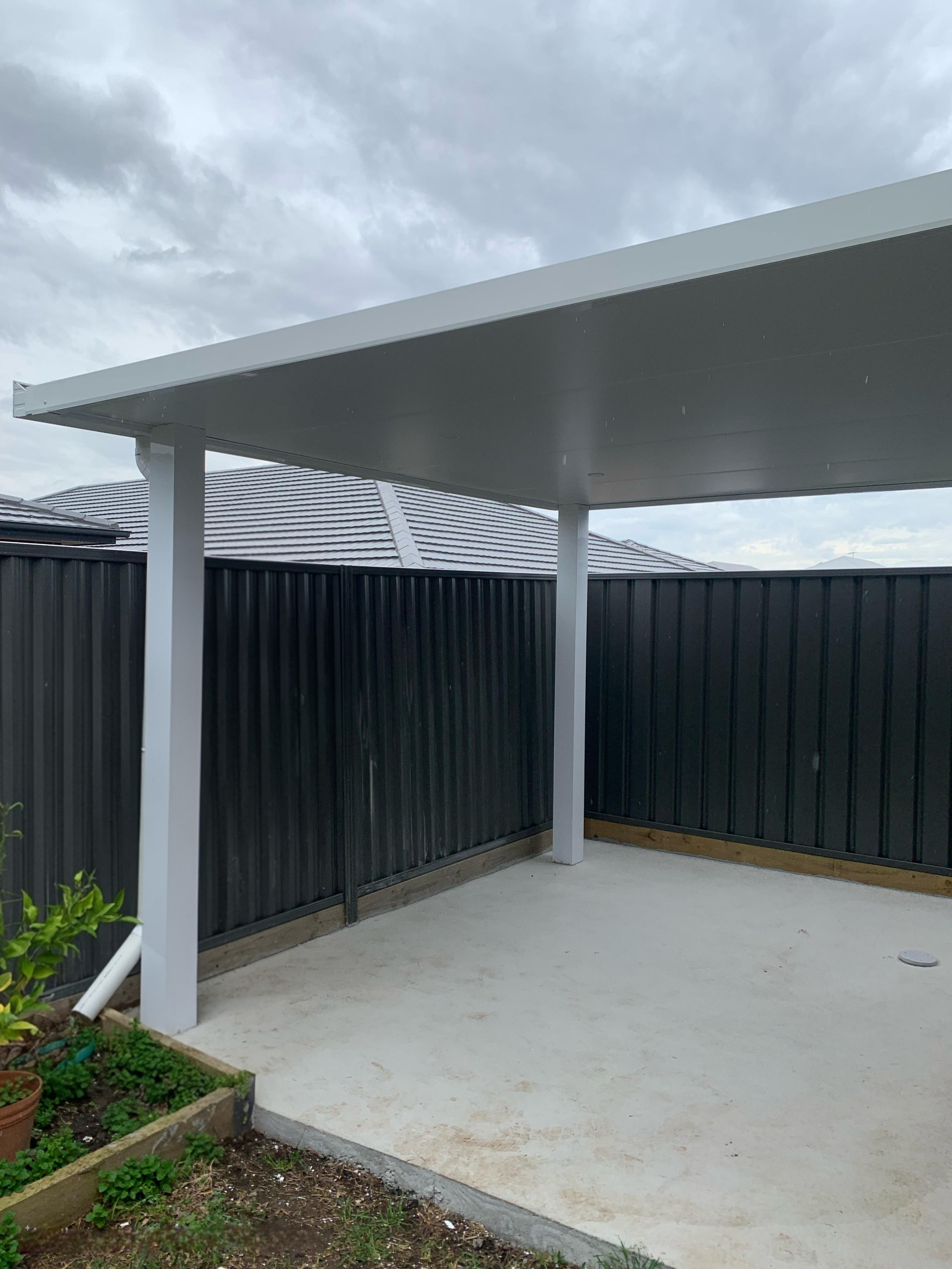 Flat-roof modern pergola with white posts, providing durable outdoor shade and low-maintenance backyard cover
