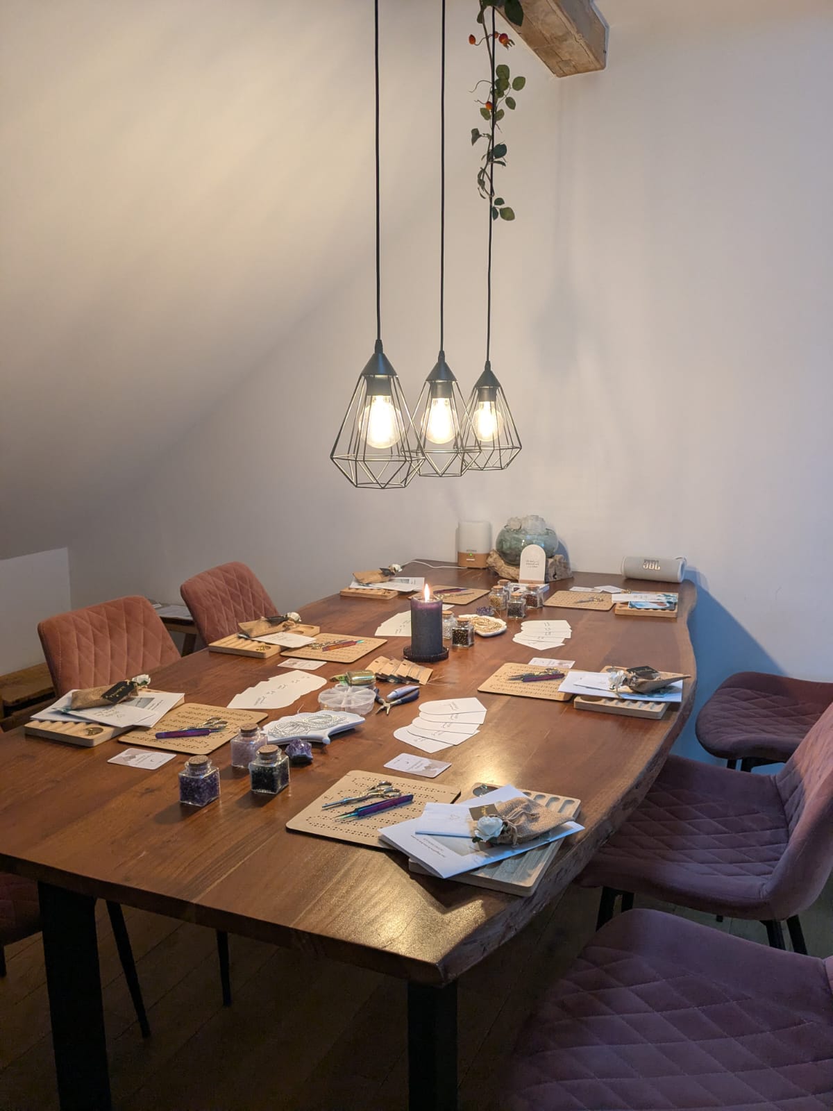 A serene and elegant spa space with wooden reclining chairs and white cushions. Golden sunlight filters through a cascading water feature, creating a peaceful atmosphere. Tropical plants and candles add to the relaxing ambiance.