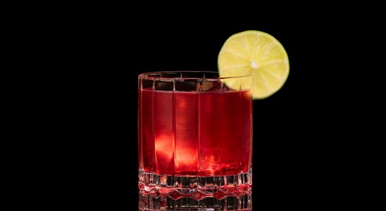 A closeup of a Vodka Cranberry drink against a dark background.