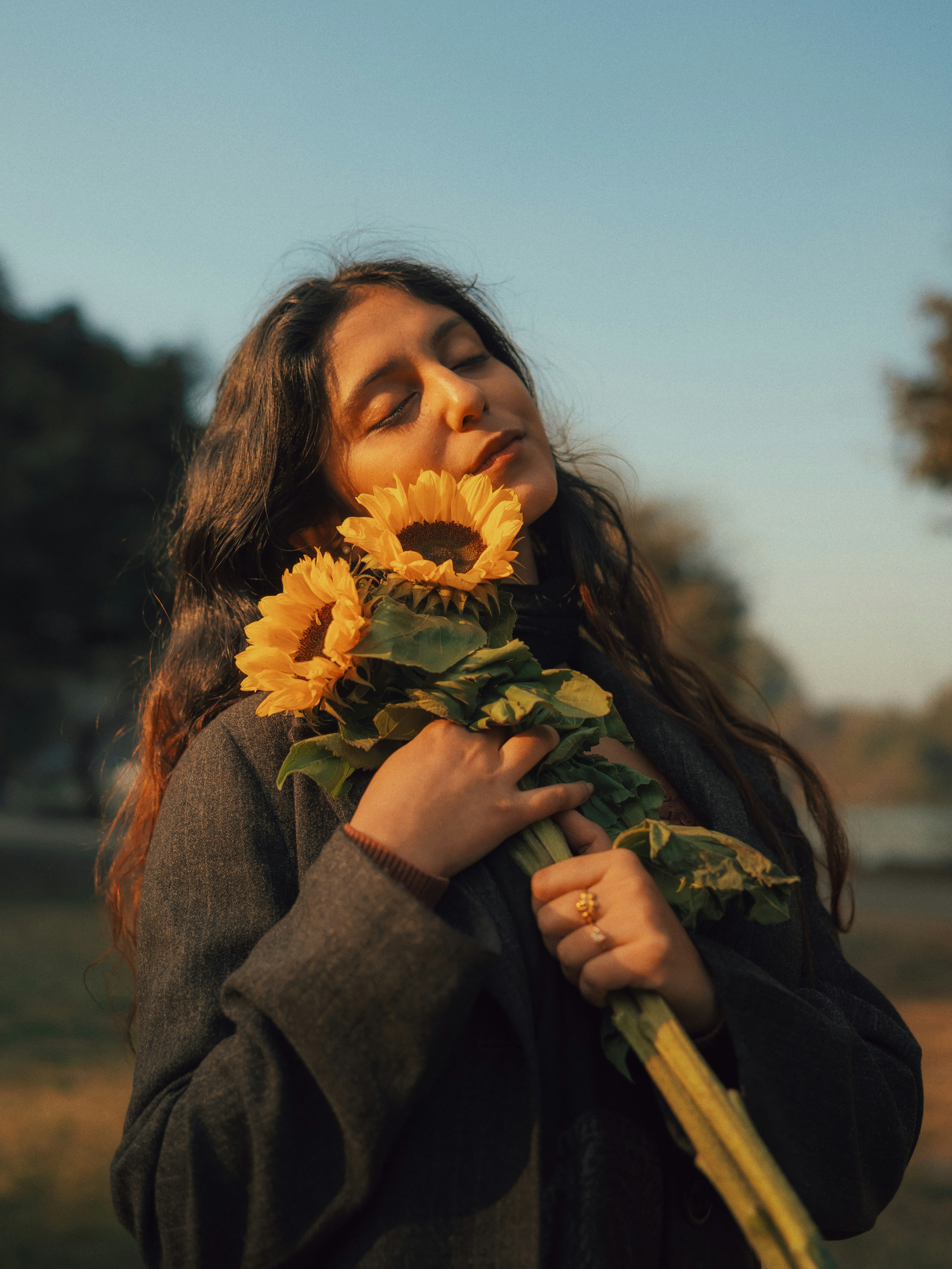 Woman holding sunflowers with eyes closed