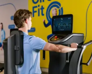 A person exercises using fitness equipment in a minimalist gym setting, focused on their workout.